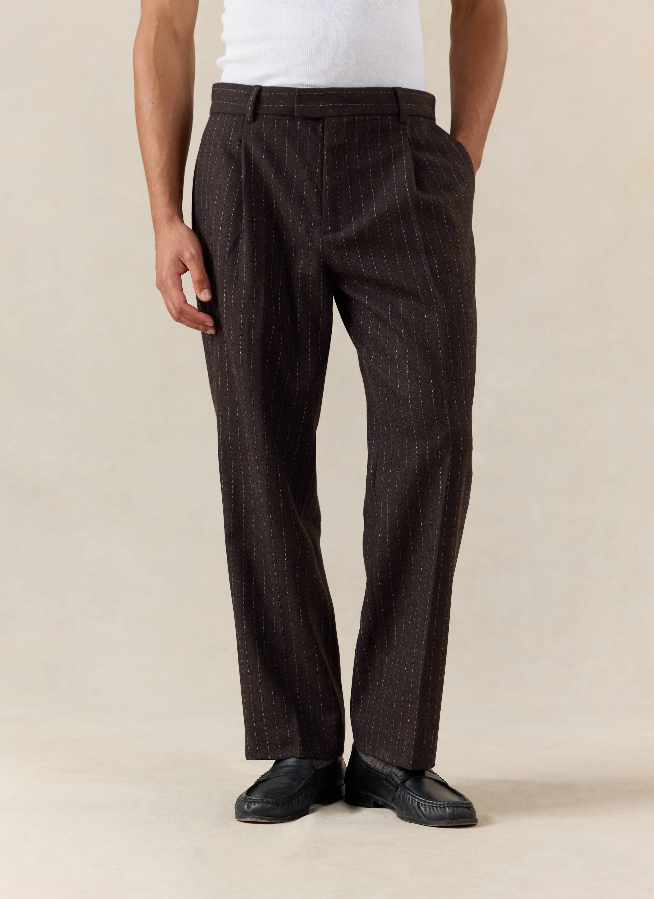 A model wears the Percival Clifton Pinstripe Pleated Tailored Trousers in espresso wool.