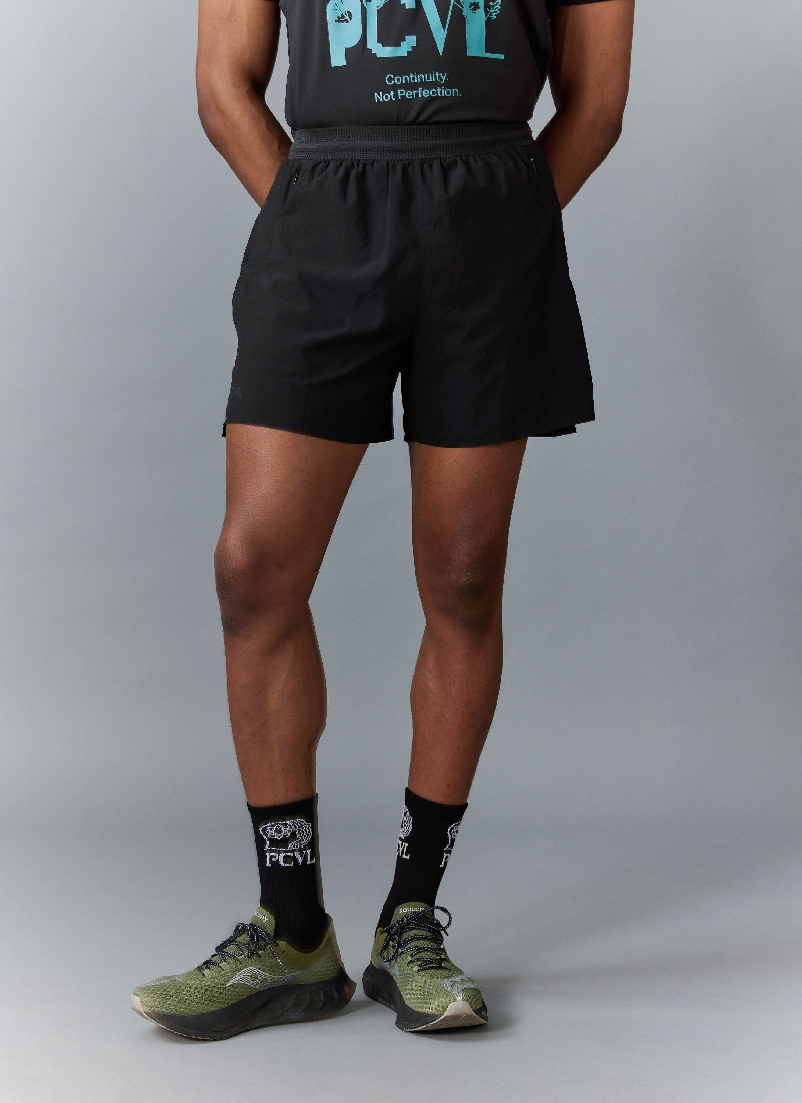 A back view of a model wearing the black PCVL Performance Shorts from Percival, showing the regular, mid-thigh fit.