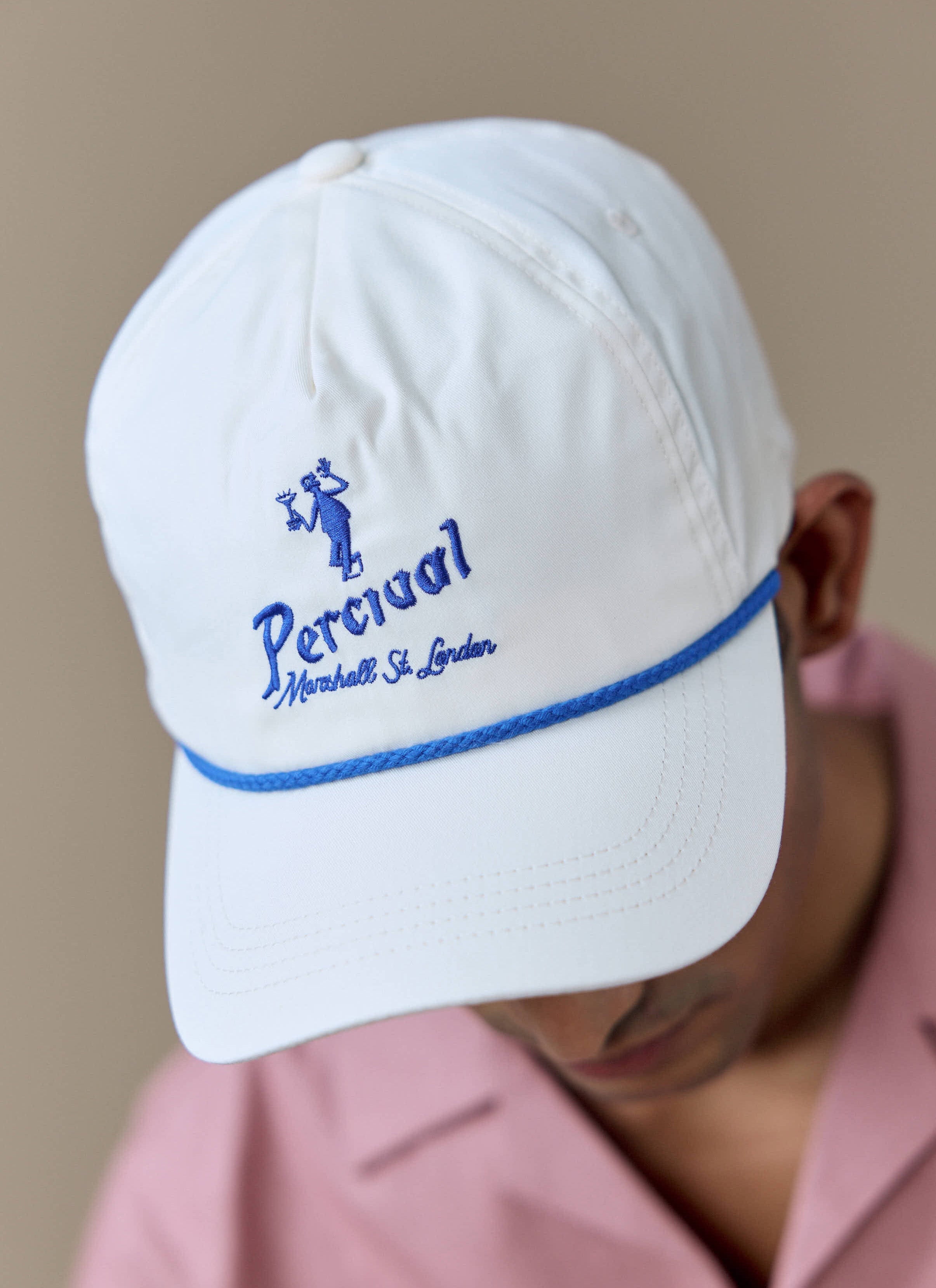 Close-up of the Percival Martini Soft Trucker Cap in cream, showing the blue martini embroidery and contrast rope detail.