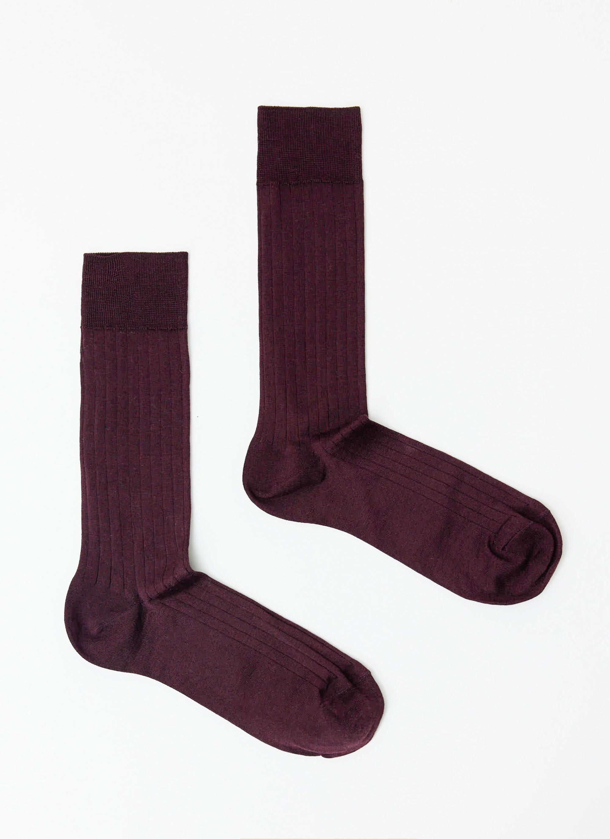 A pair of Percival Loafer Dress Socks in merlot, made from a ribbed cotton, laid flat against a white background.