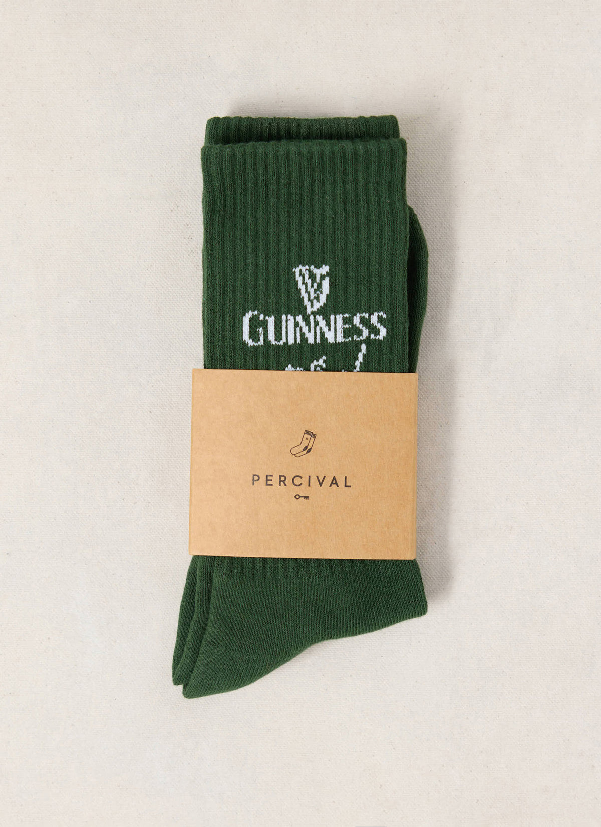 Forest green Guinness x Percival crew socks featuring a ribbed cotton texture and a branded cardboard wrapper.