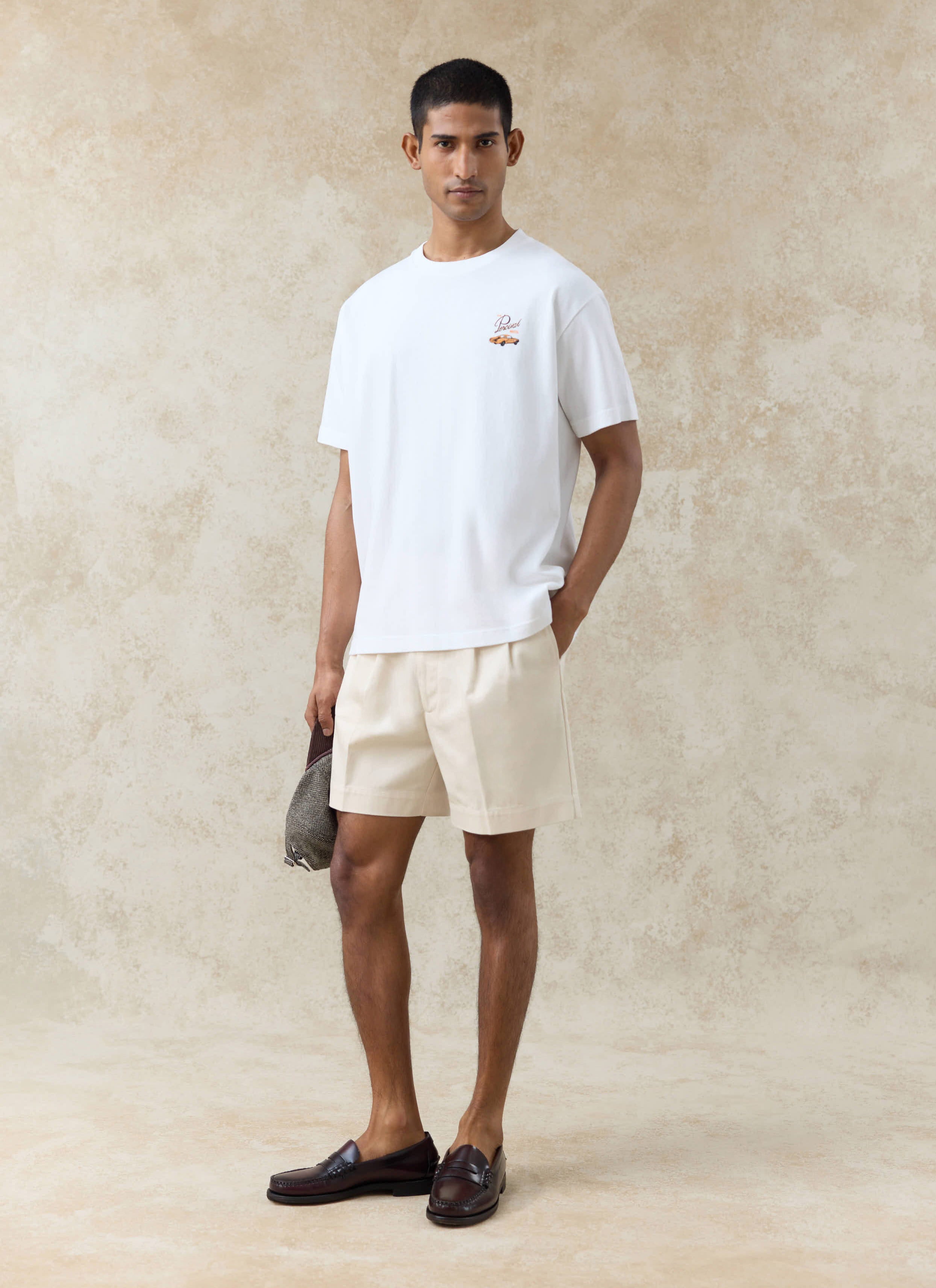 White Percival Alistair oversized graphic t-shirt and cream Blake double pleated cotton shorts on a standing model.