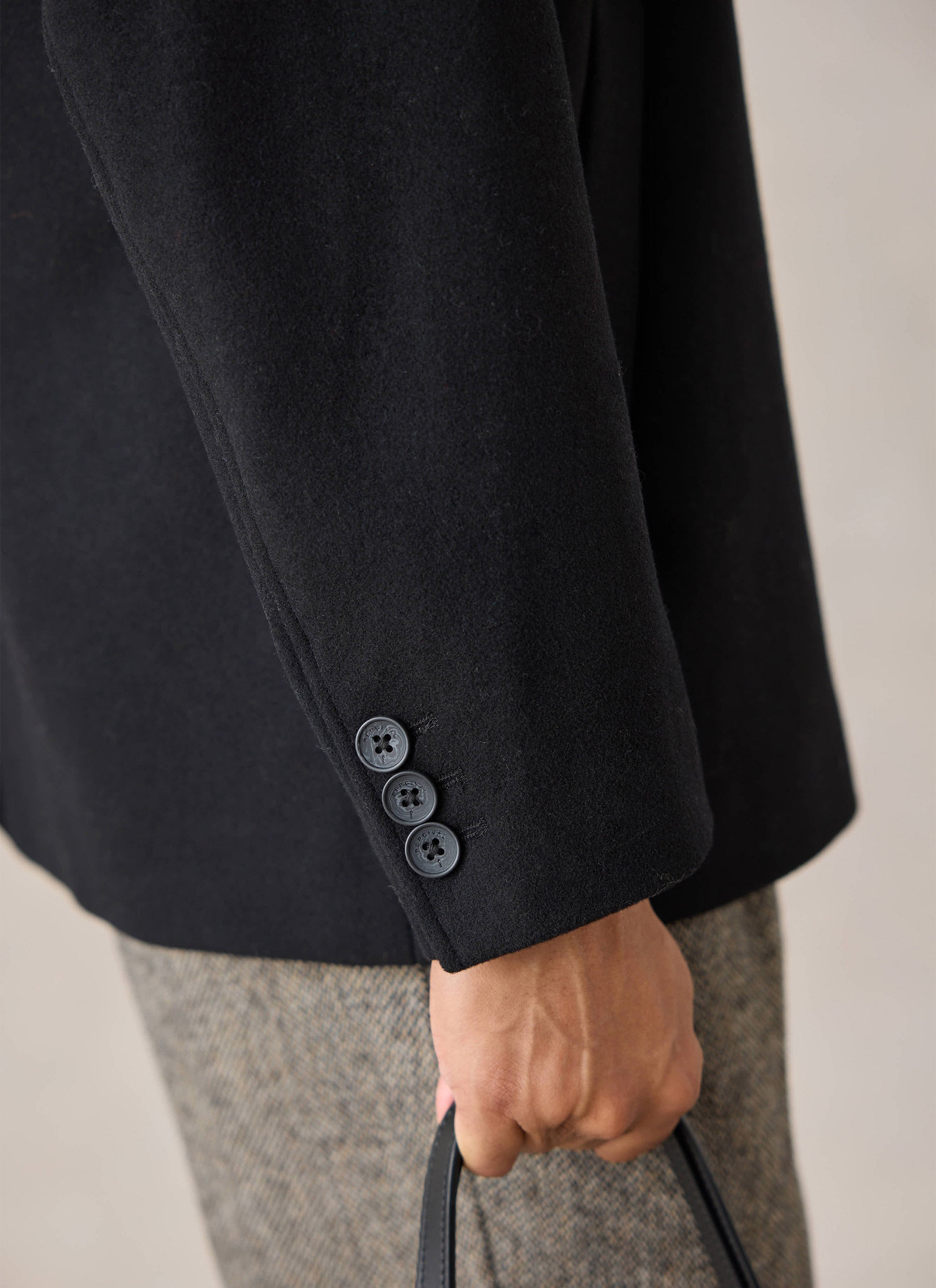 A close-up view of the sleeve and button detail on the black Melton Wool peacoat from Percival.