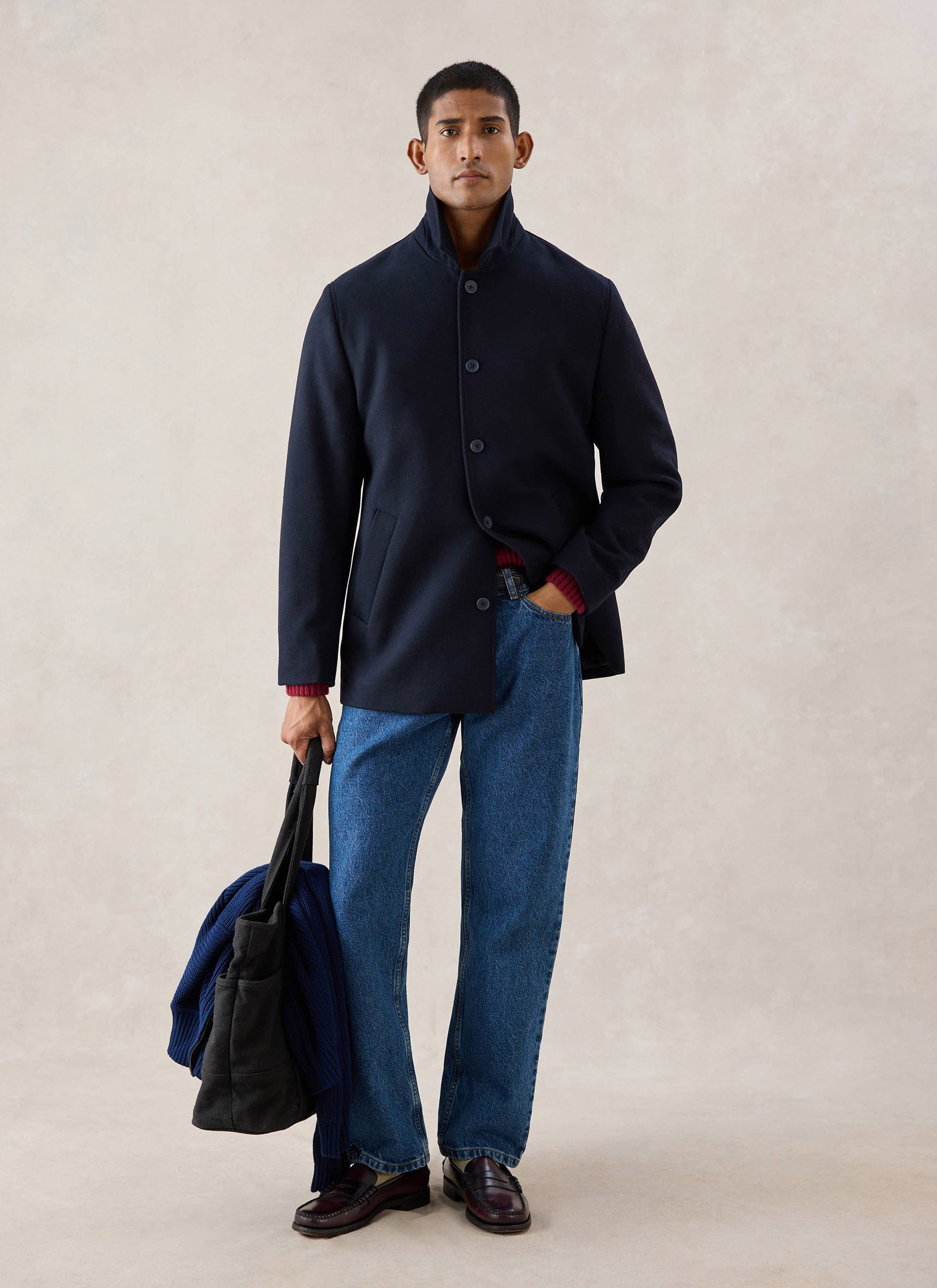 A model wearing the navy Percival wool blend peacoat with a high collar, styled with jeans and holding a dark bag.