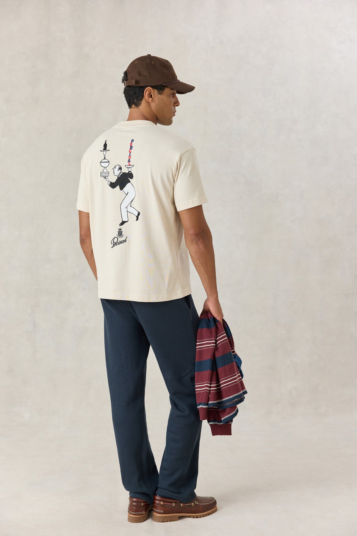 A model from the back wearing the Percival cream oversized T-shirt with the illustrated waiter graphic printed on the back.