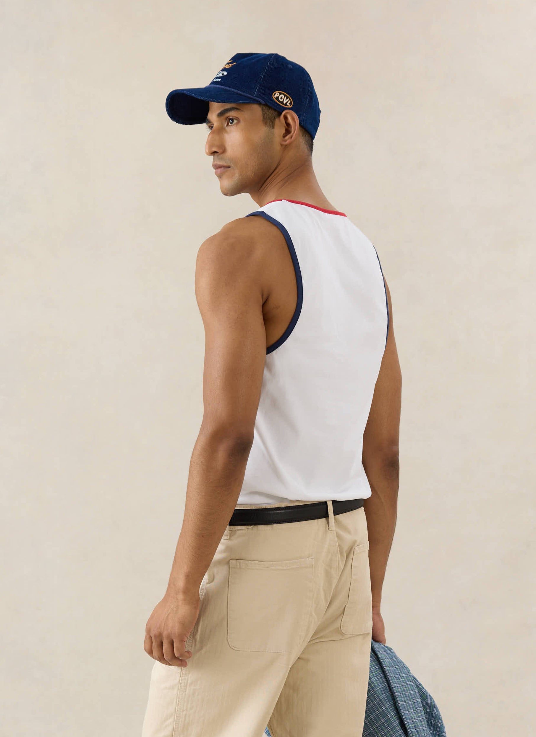 White Ford x Percival GT40 Ringer Vest in organic cotton, paired with beige trousers and a navy corduroy cap.