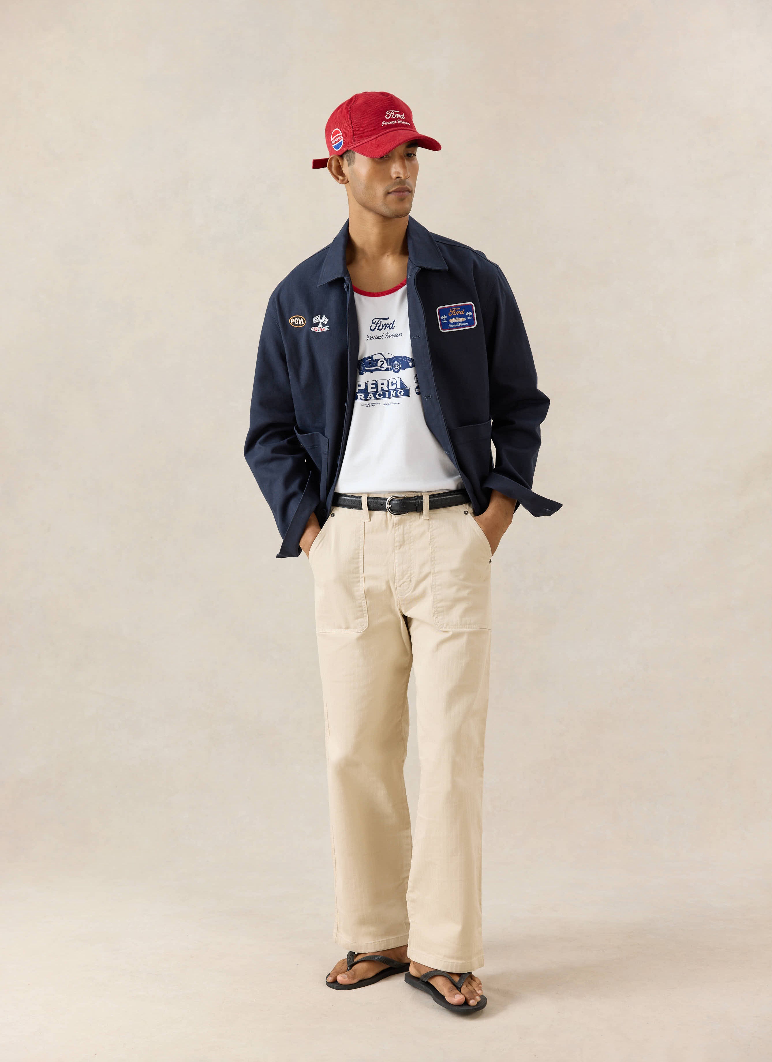 White Ford x Percival GT40 ringer vest styled with a navy patch jacket, cream trousers, and a red Ford cap.