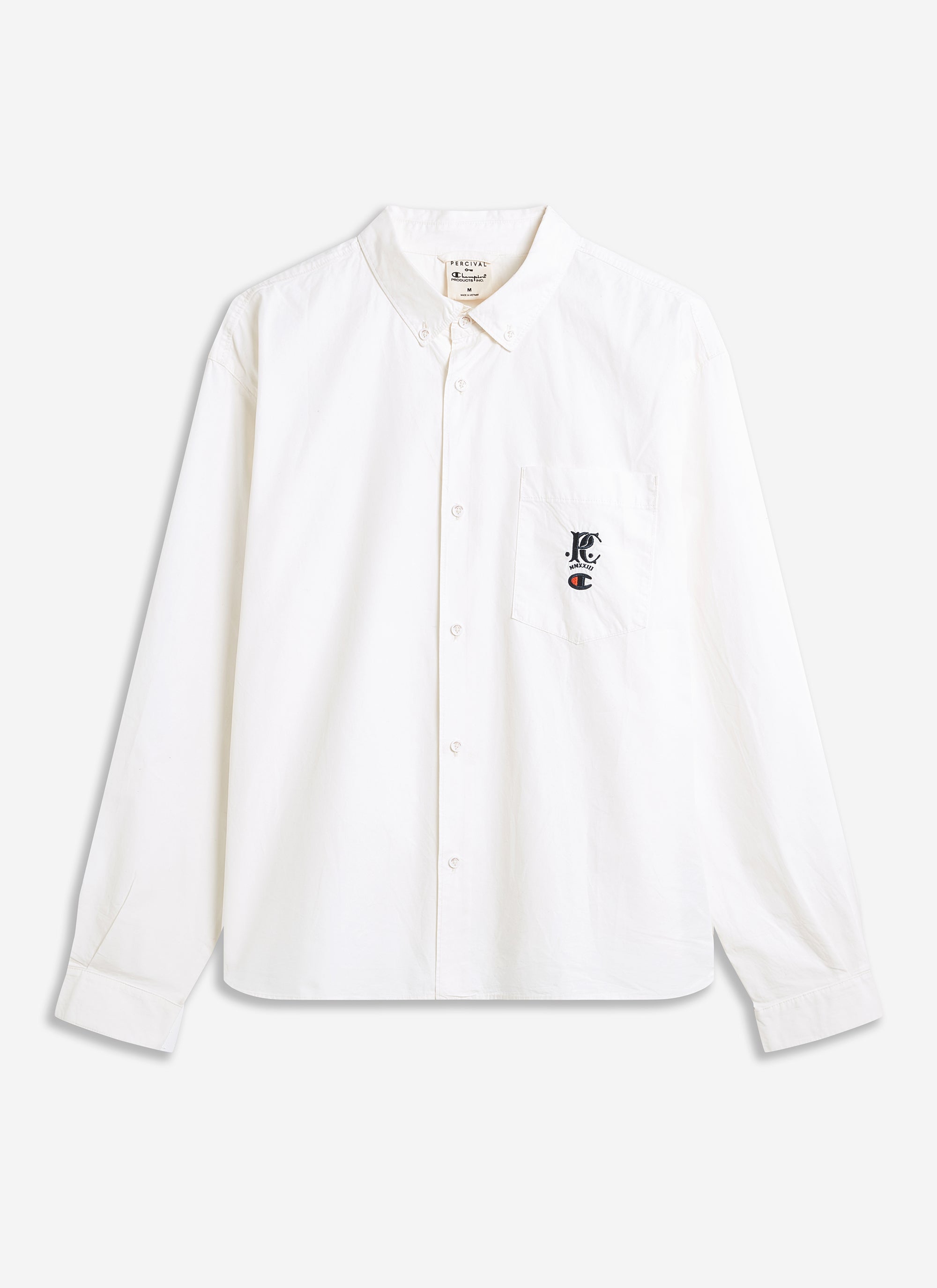 The Champion x Percival Relaxed Oxford Shirt in ecru, shown in a flat lay photograph highlighting the embroidered chest logo.