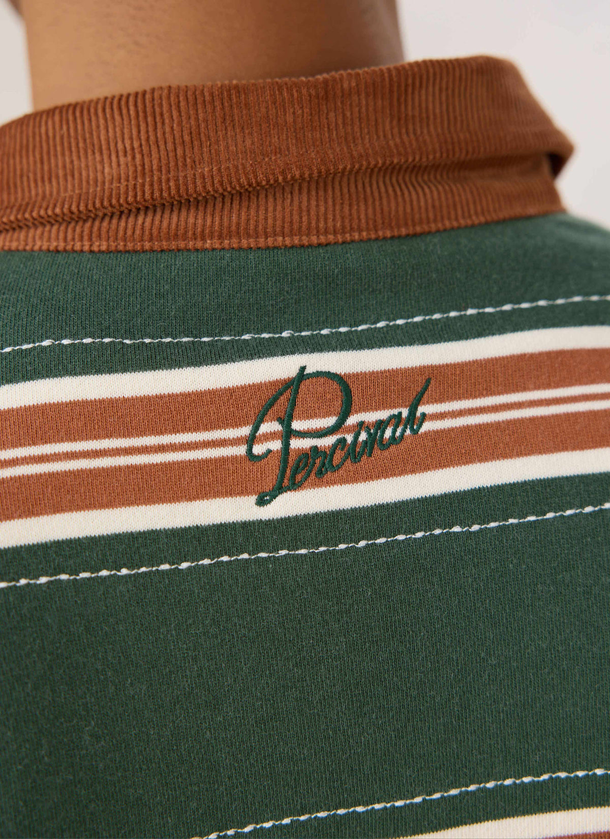 Close-up of the Guinness x Percival rugby polo in green stripe, highlighting the brown cord collar and back embroidery.