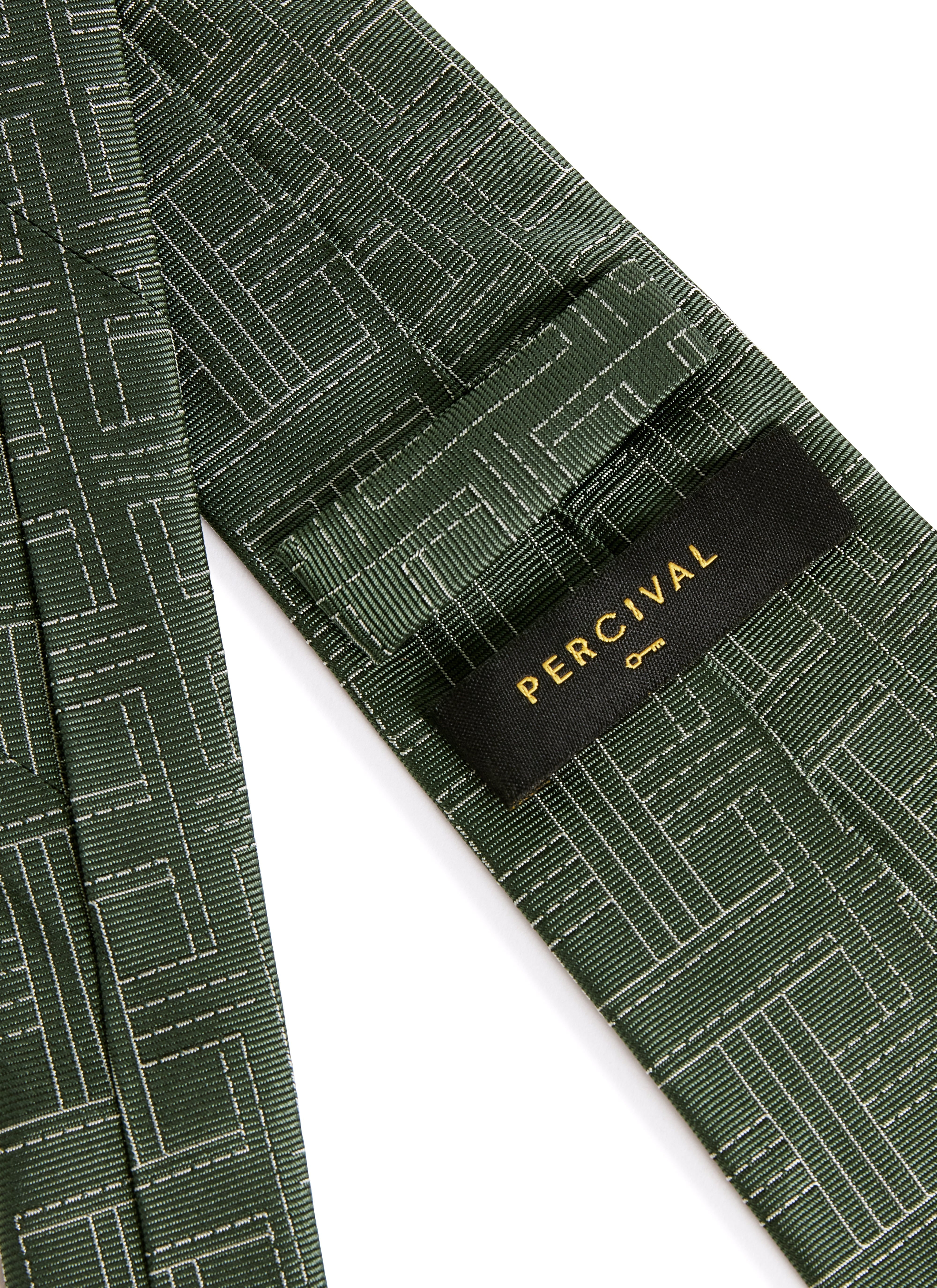 Close-up of the back of the Percival Sashiko Tie in forest green silk, showing the brand label and textured weave.