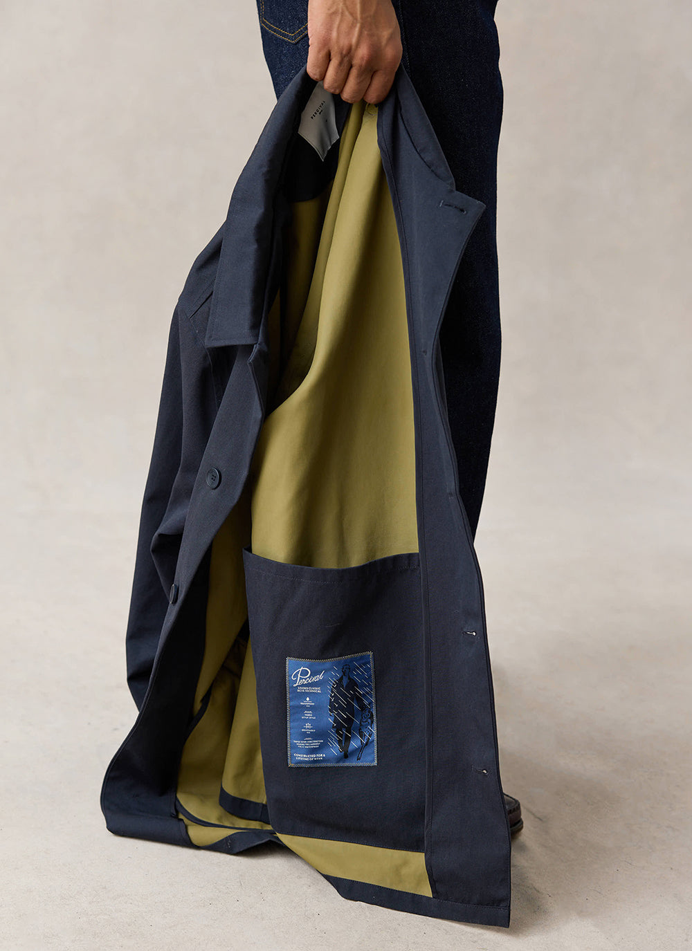 Close-up of the olive interior and large internal pocket on the Percival navy Sherlock trench coat.