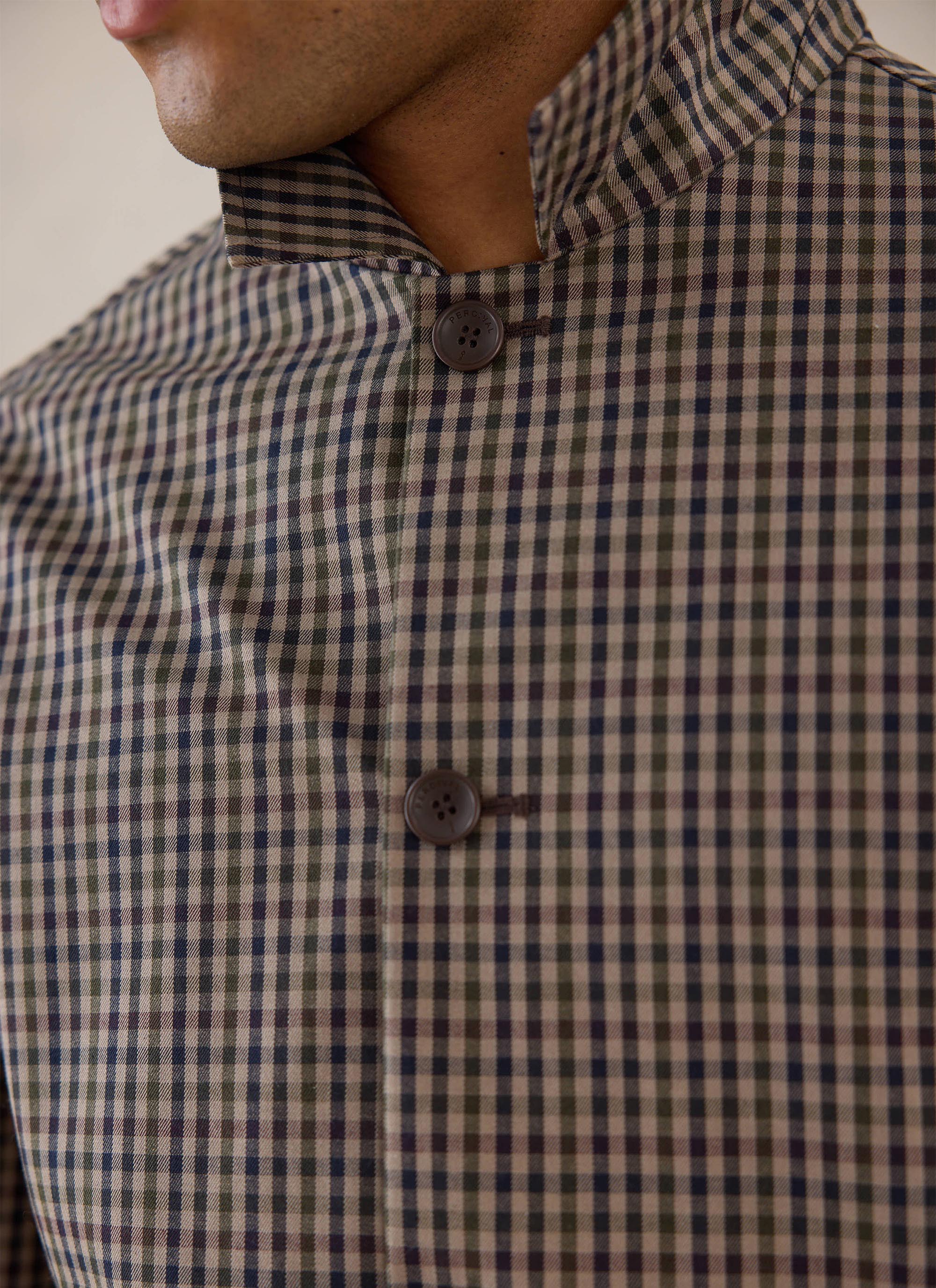 Close-up of the Watcher Check pattern and buttons on the Percival Sherlock Short Trench Coat.
