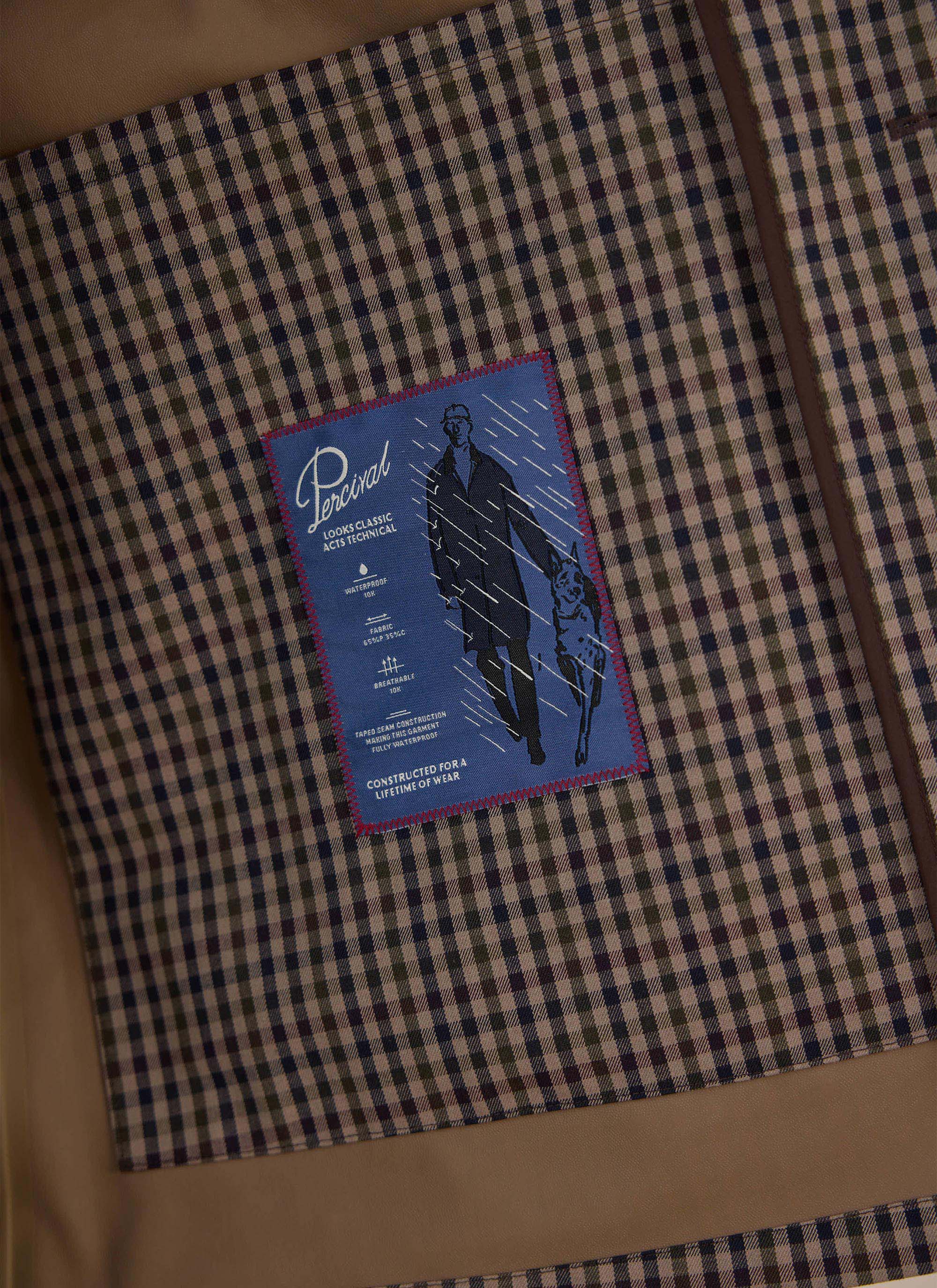 A close-up of the internal screen-printed technical details label inside the Percival Sherlock Short Trench Coat.