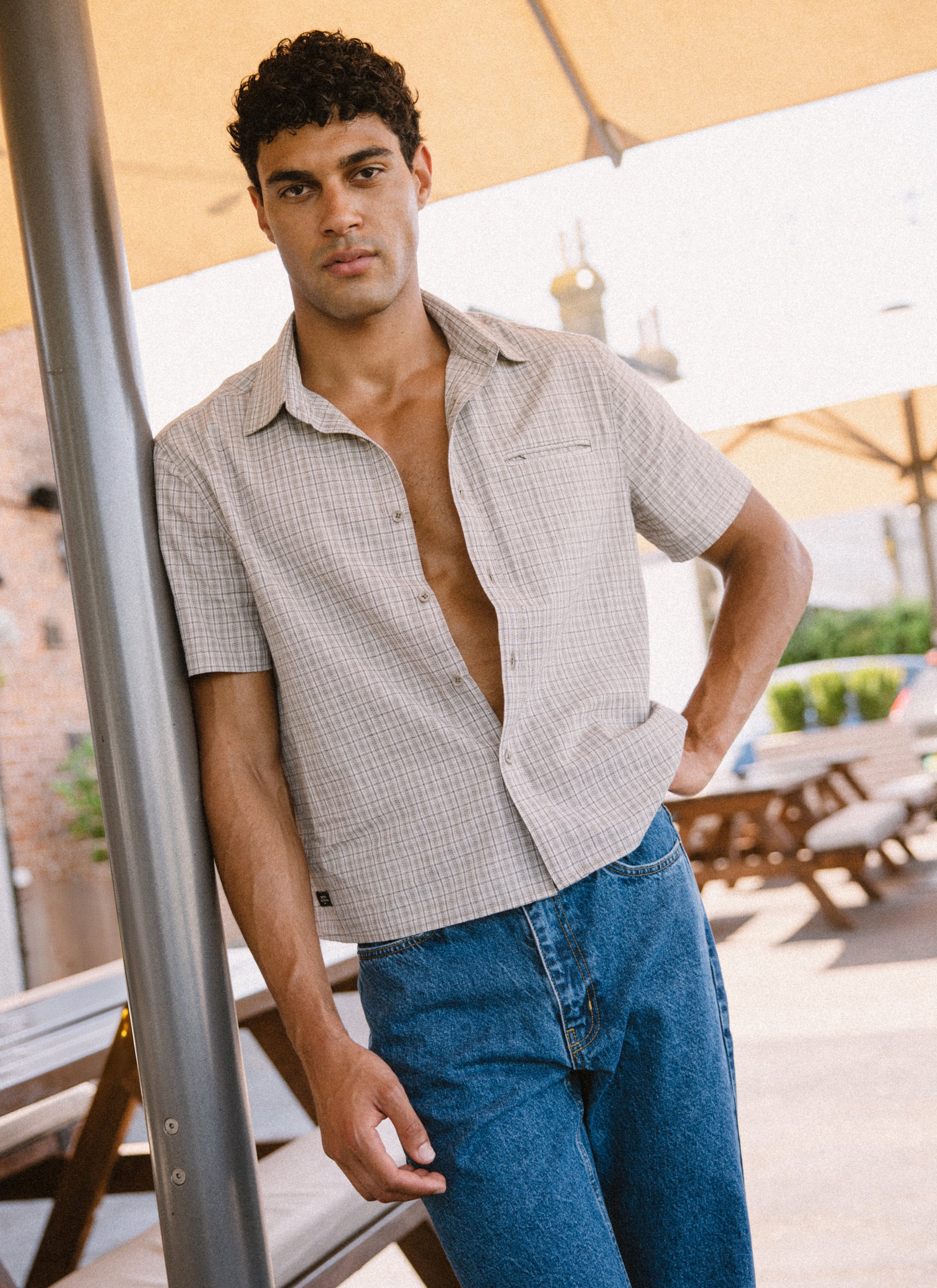 Percival Hinsley boxy cream check 100% cotton short sleeve shirt, paired with mid-wash blue heritage denim jeans.