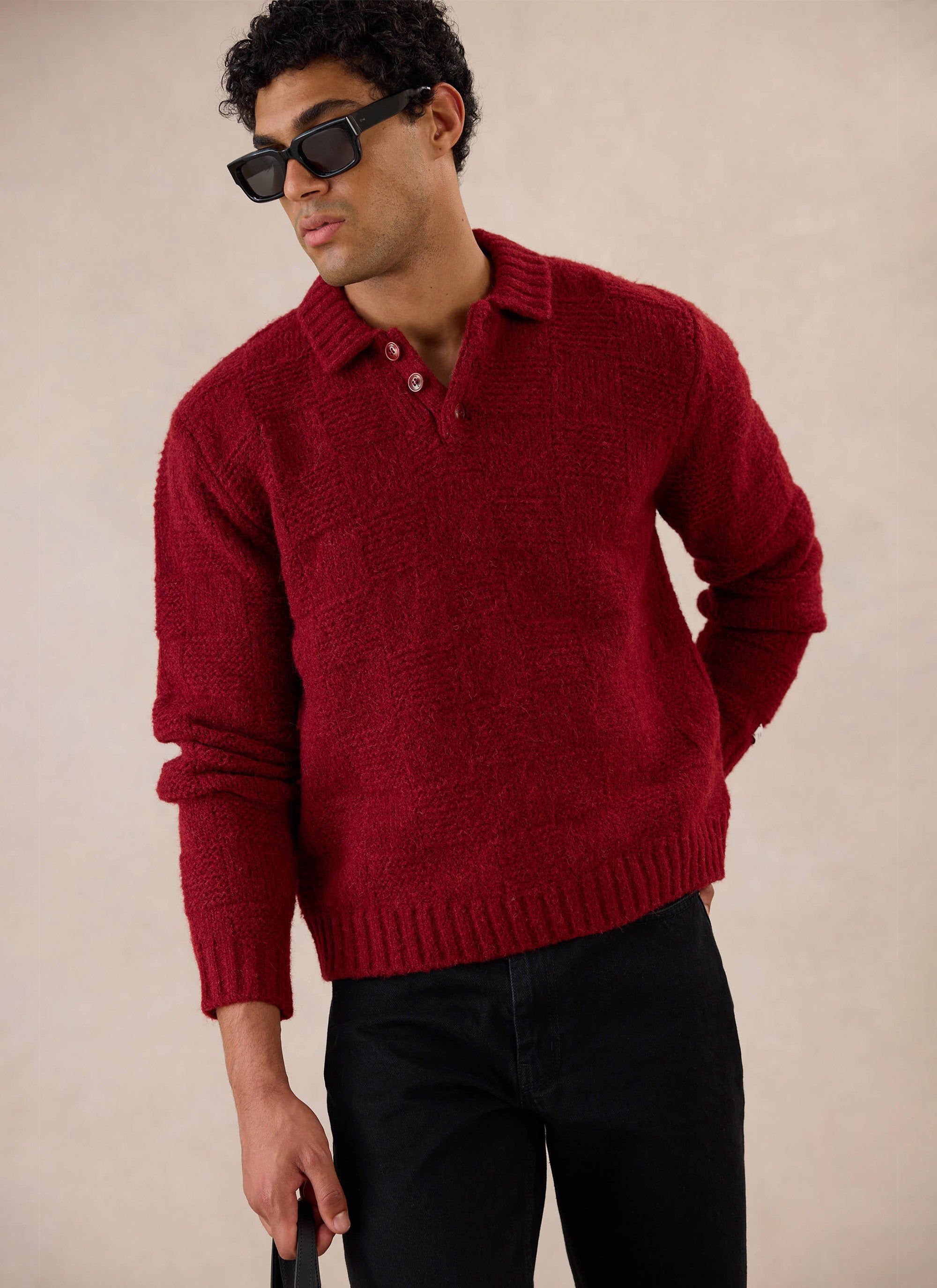 A model wears the burgundy Percival Shugart Knit Jumper in a studio setting, featuring a button neck and textured finish.