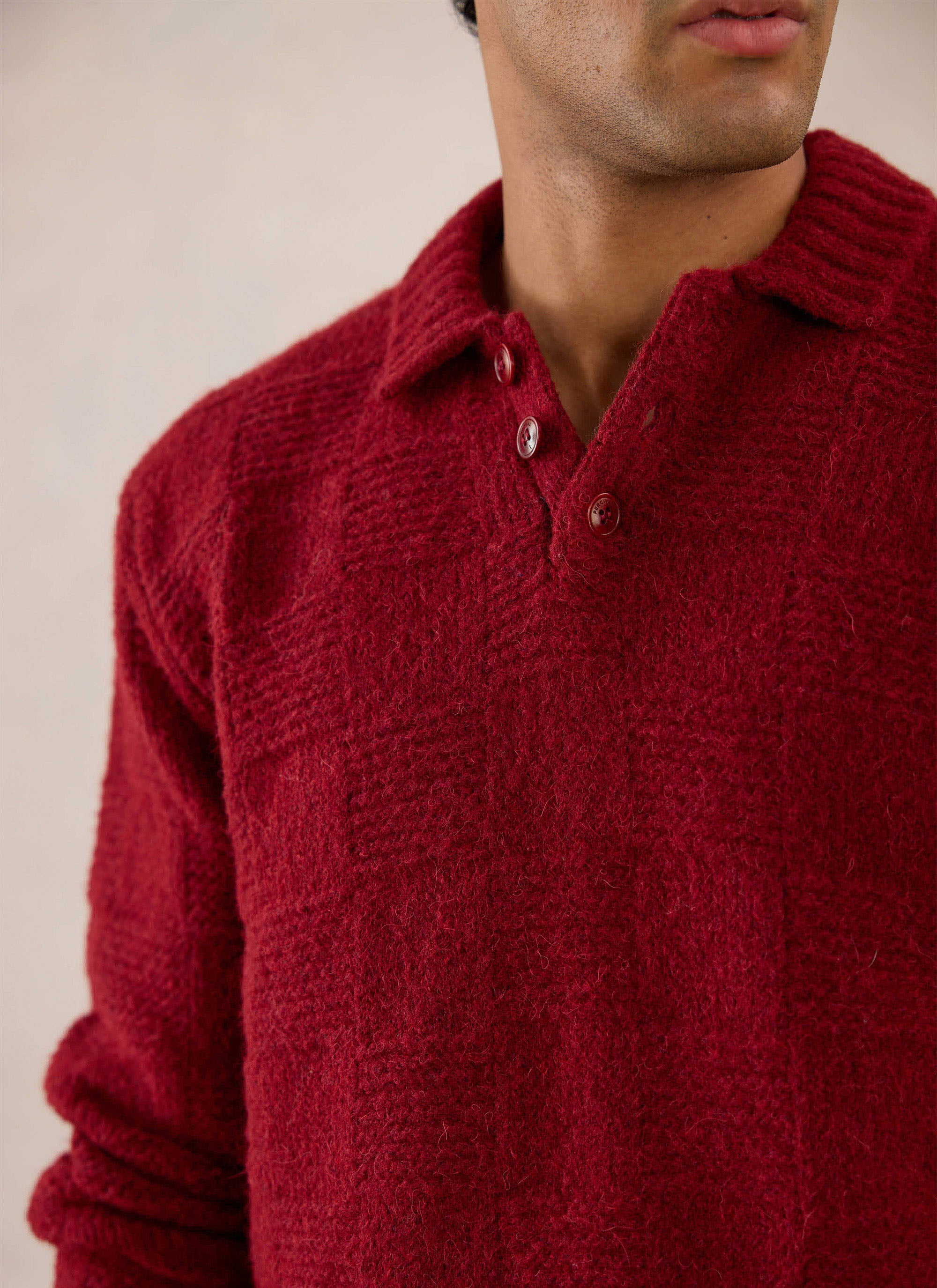 A close-up of a model wearing the merlot Percival Shugart Boxy Knit Jumper, showcasing the button collar and textured knit.