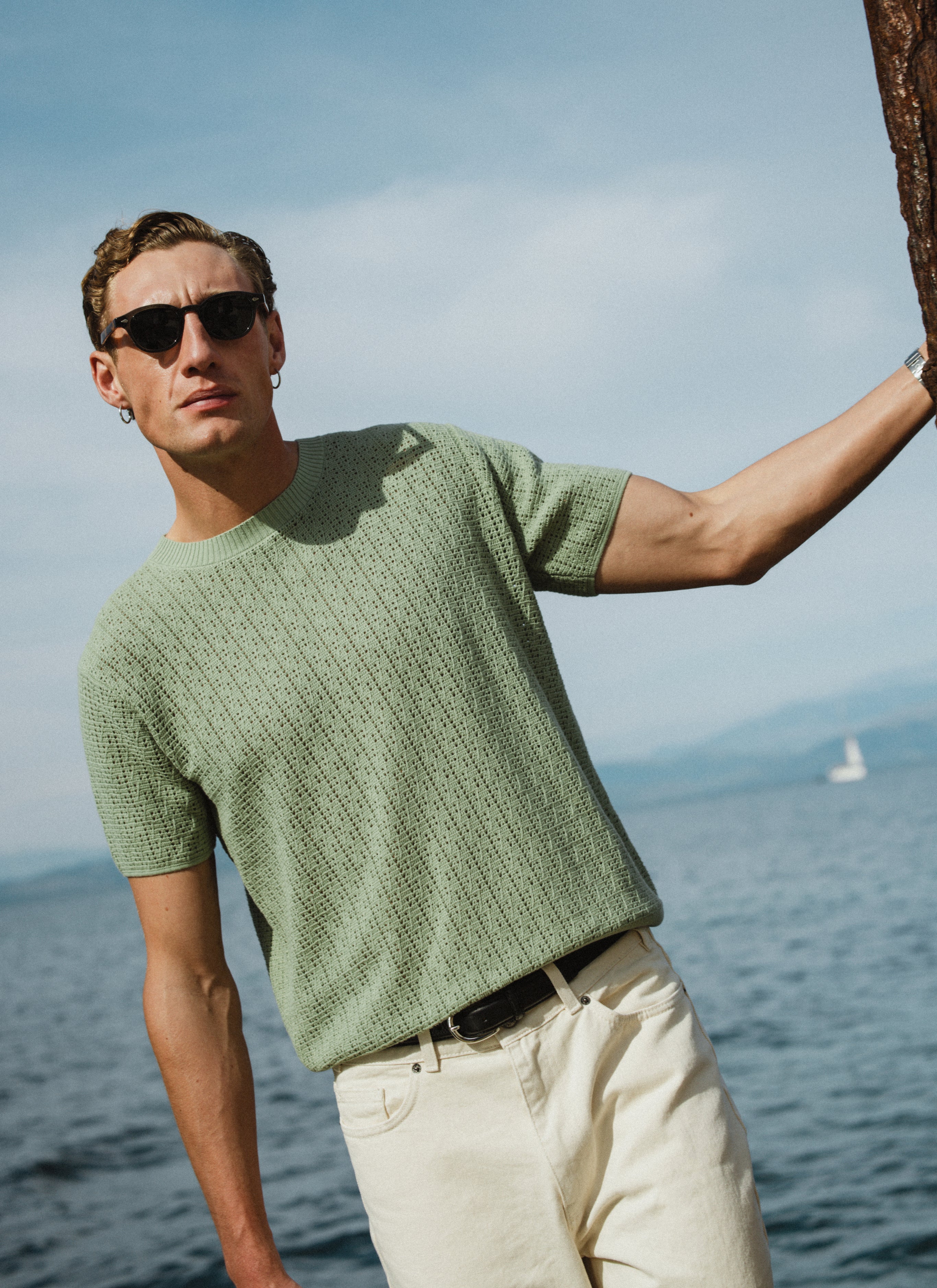 Percival Siena knitted T-shirt in pistachio green pointelle cotton, worn by a model outdoors by the sea.