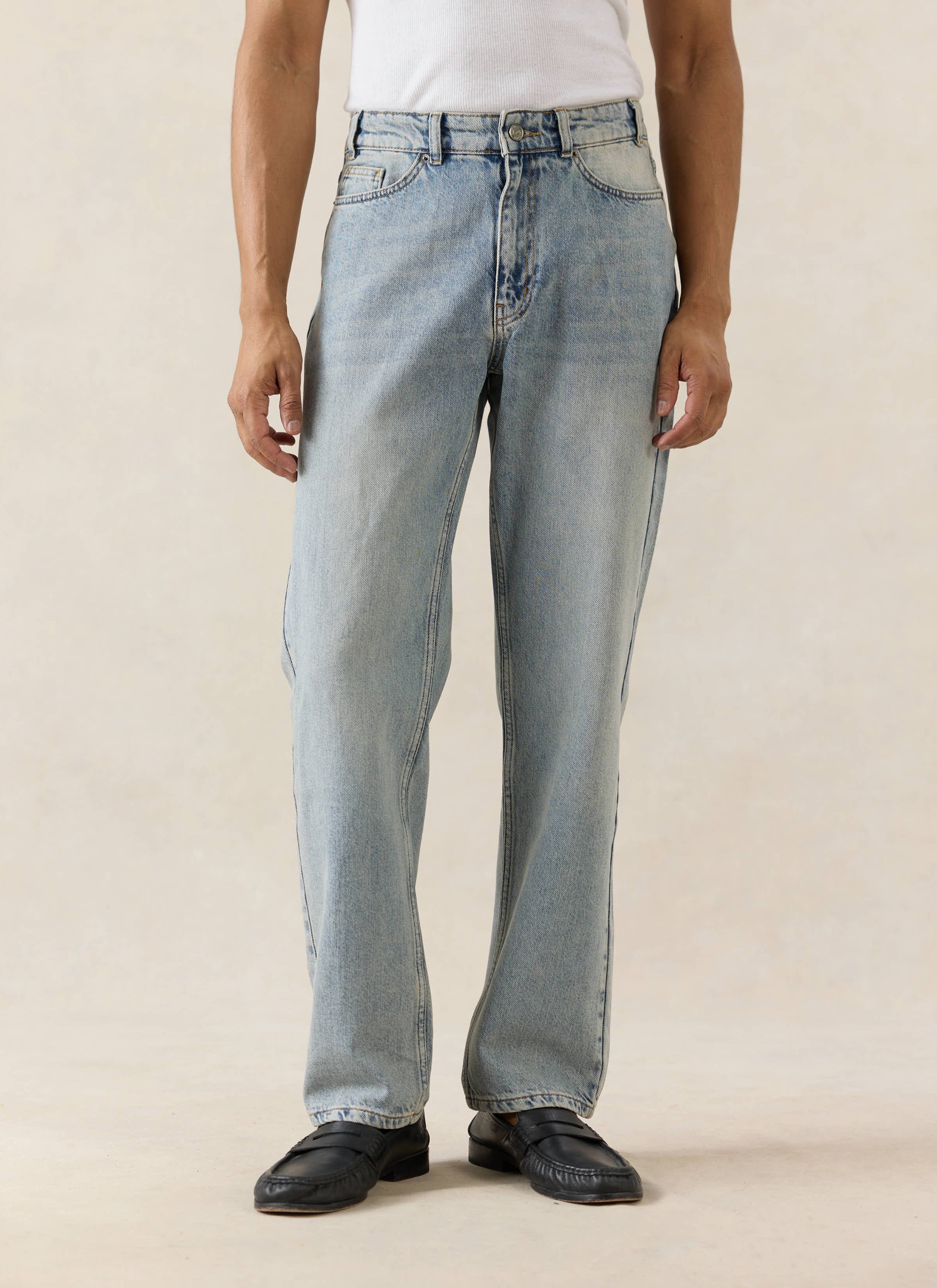Percival stone wash straight leg jeans in 12oz denim, styled with a white vest and black leather loafers.