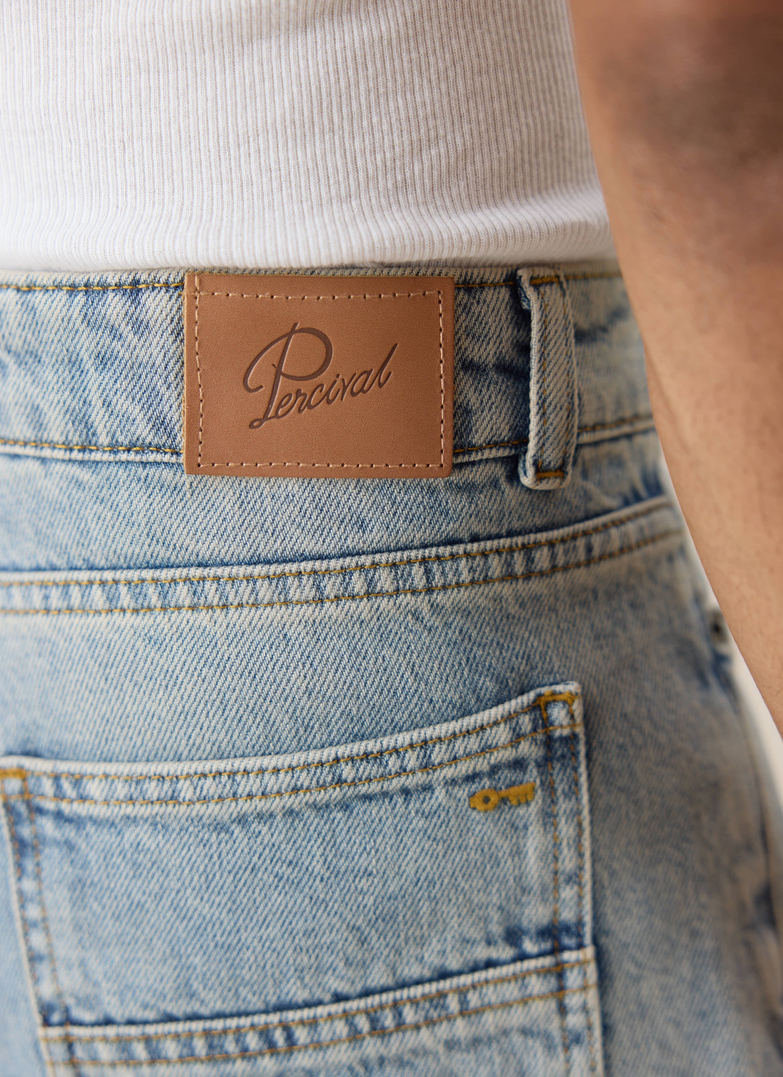 Percival stone wash denim jeans, featuring the signature tan leather back patch and gold embroidered key detail.