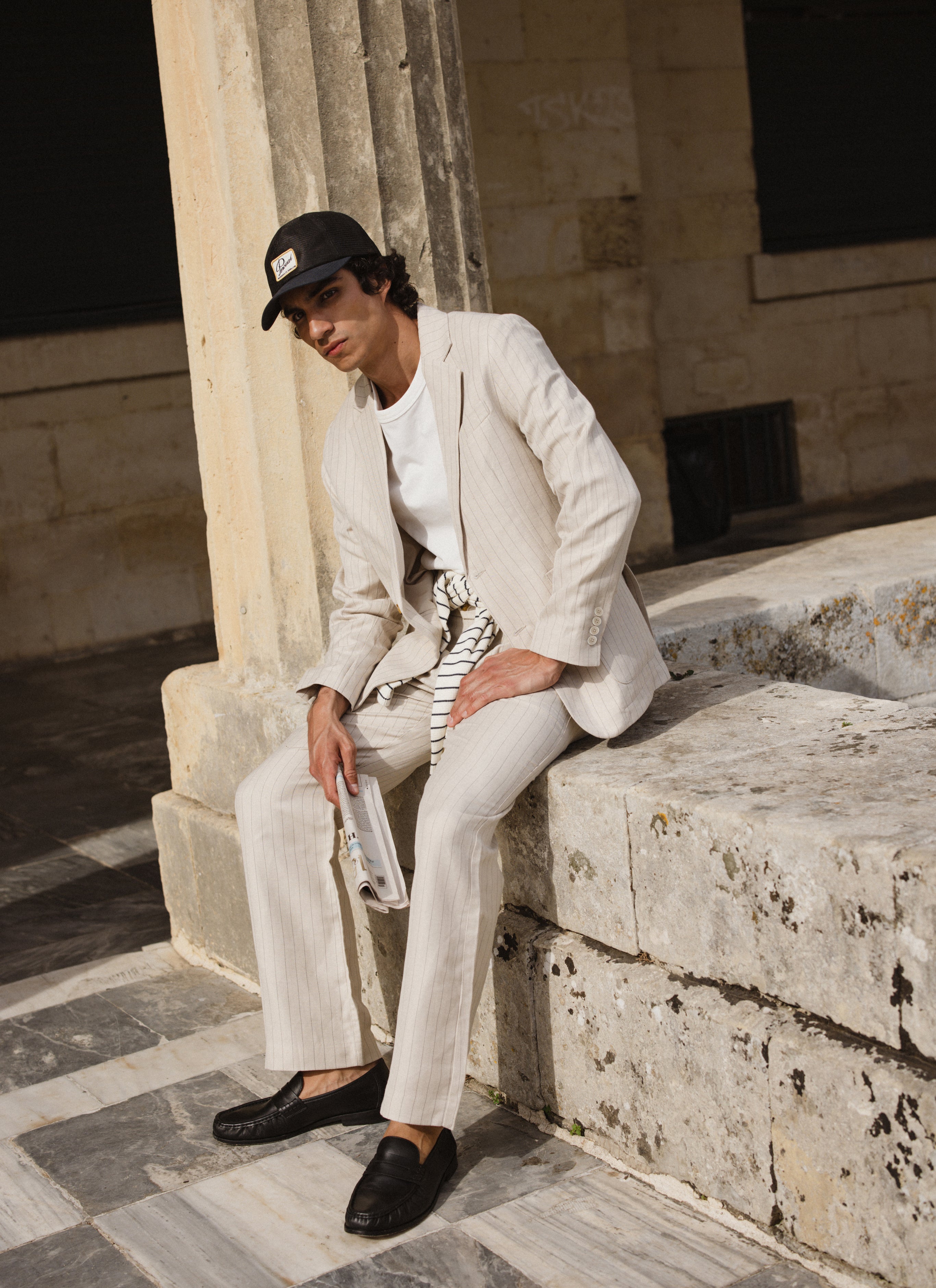 A model wears the cream Percival striped tailored blazer and trousers, styled with a white t-shirt and black loafers.