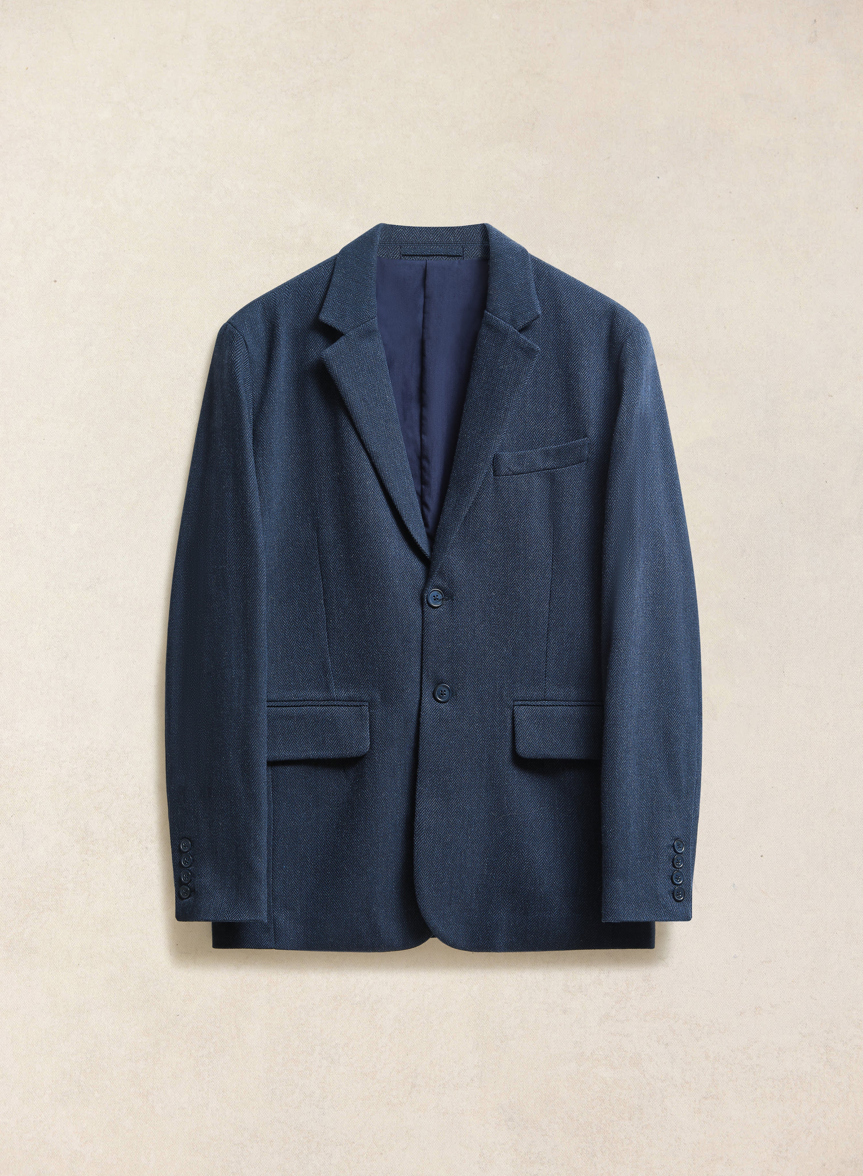 The navy herringbone wool-blend tailored blazer from Percival, featuring notch lapels and flap pockets.