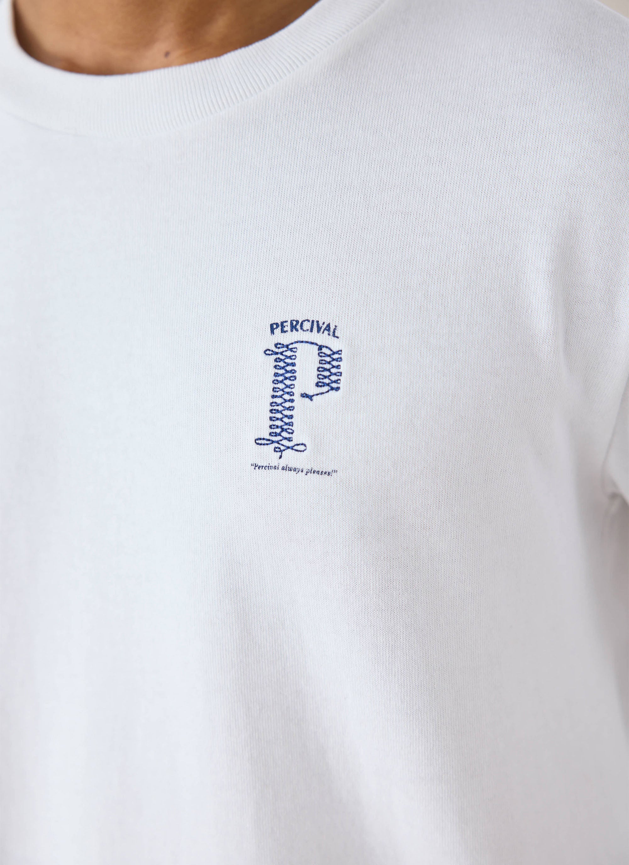 Close-up of a model wearing the white Percival Tucker long sleeve t-shirt, highlighting the chest embroidery.