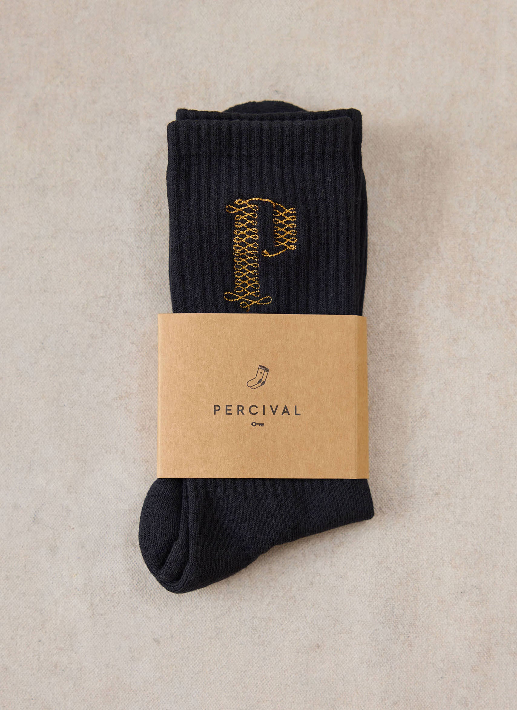 A pair of black Percival Tucker embroidered socks wrapped with a branded paper band.