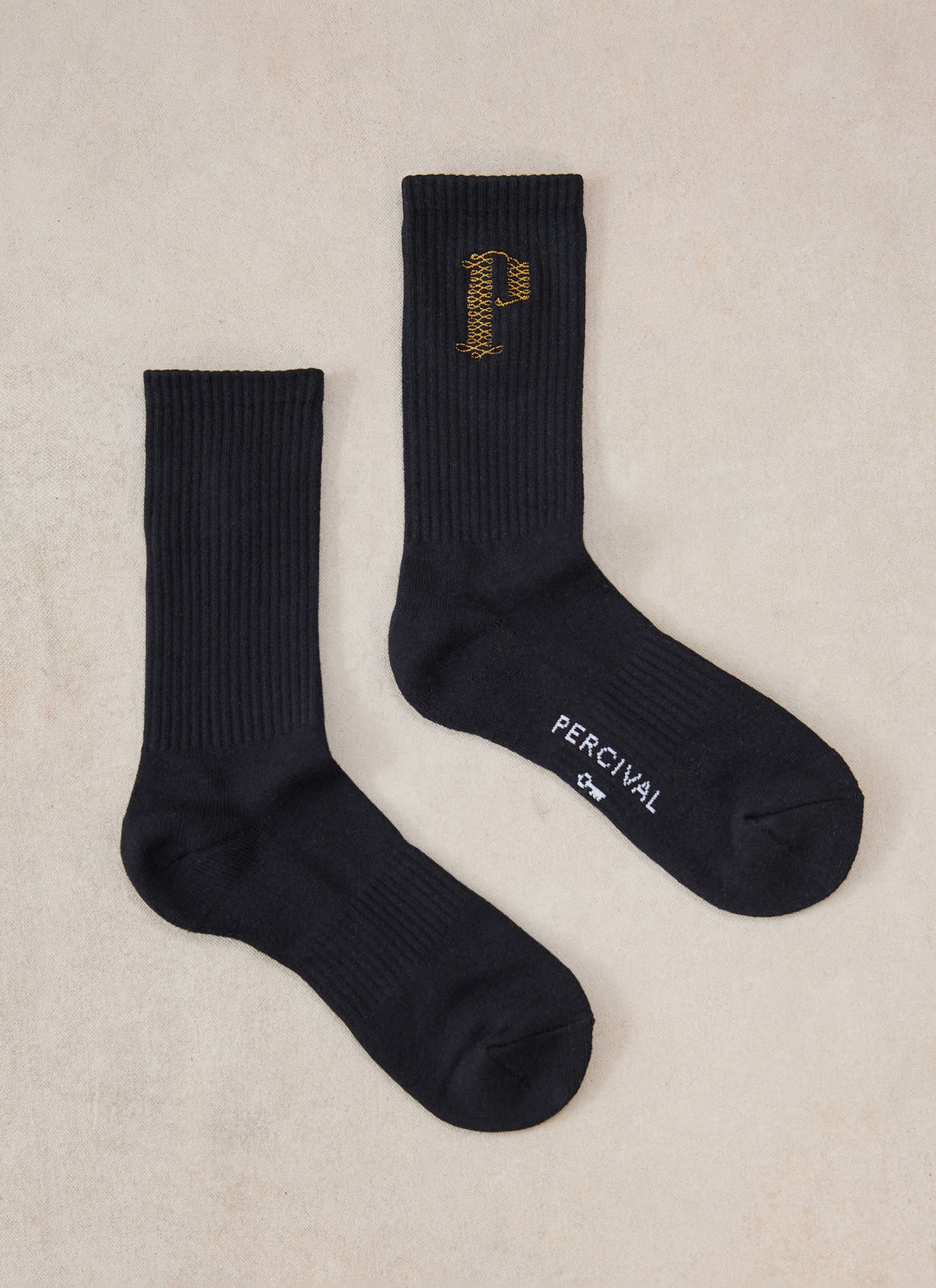 Black Percival Tucker embroidered crew socks in a flat lay, featuring a ribbed cotton blend and gold embroidered P detail.