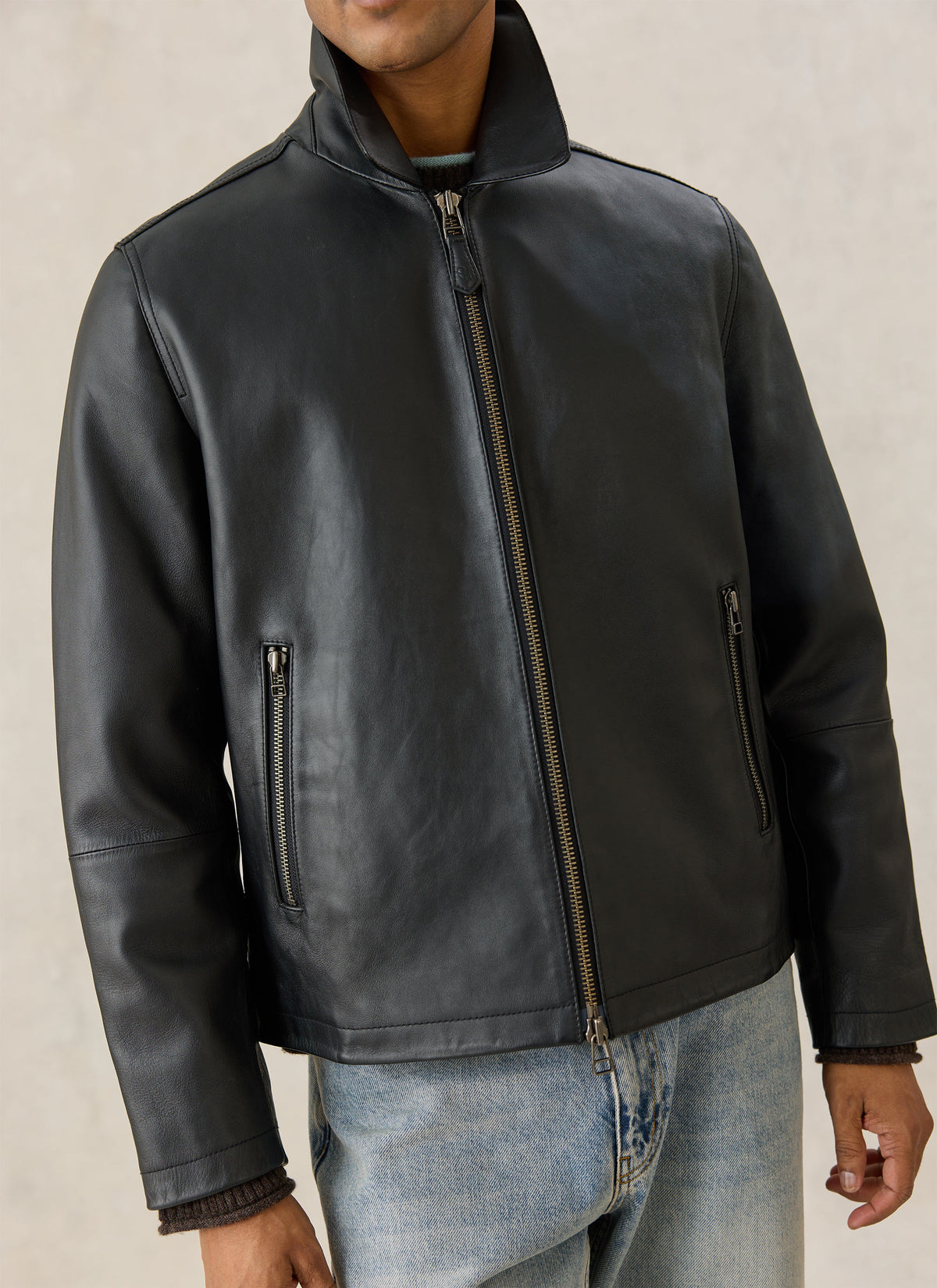 A close-up of the Percival Turner black leather zip jacket, showing the clean front zip and zipped side pockets.