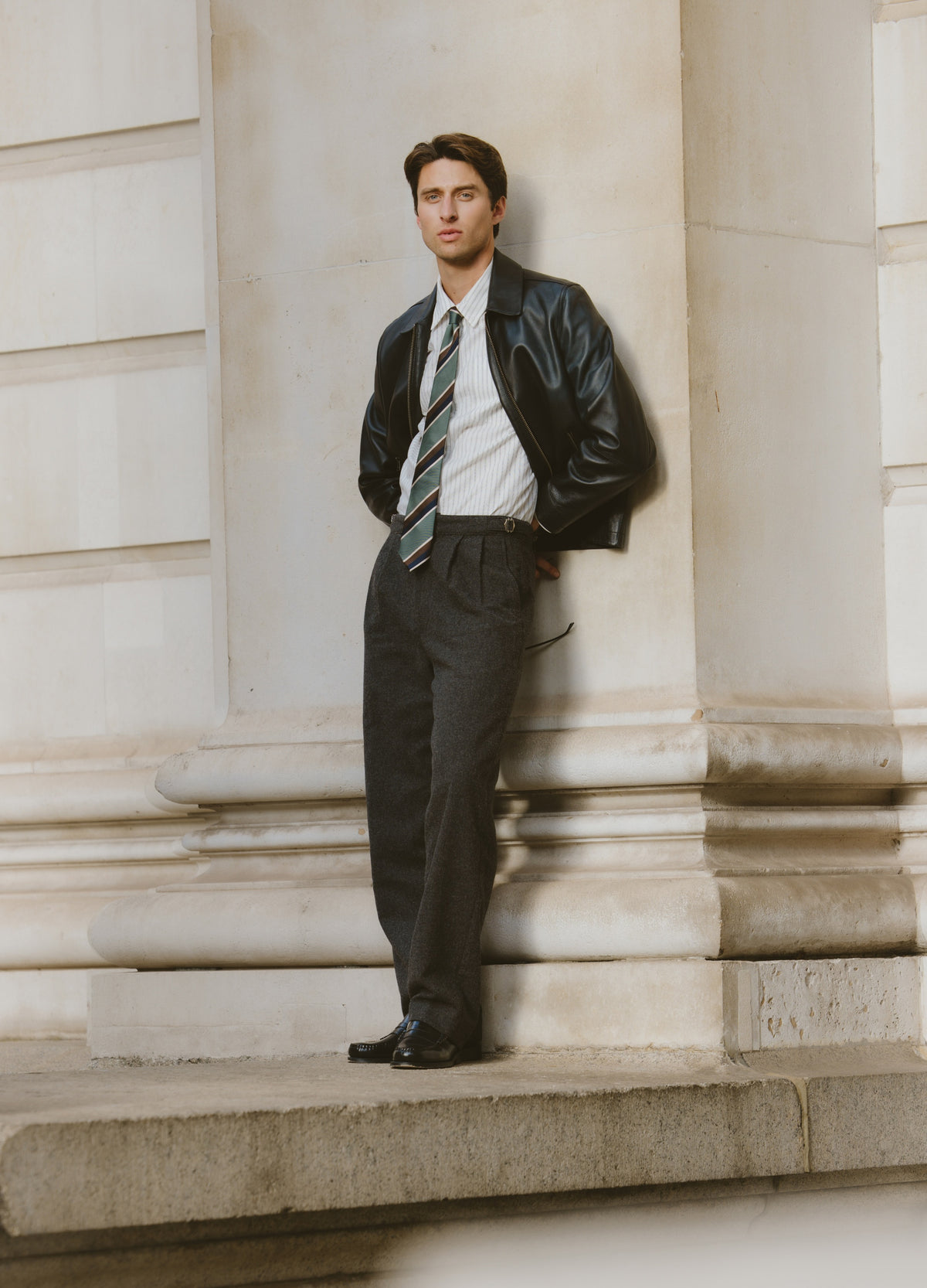 Model wearing Percival charcoal trousers, leather jacket and tie.