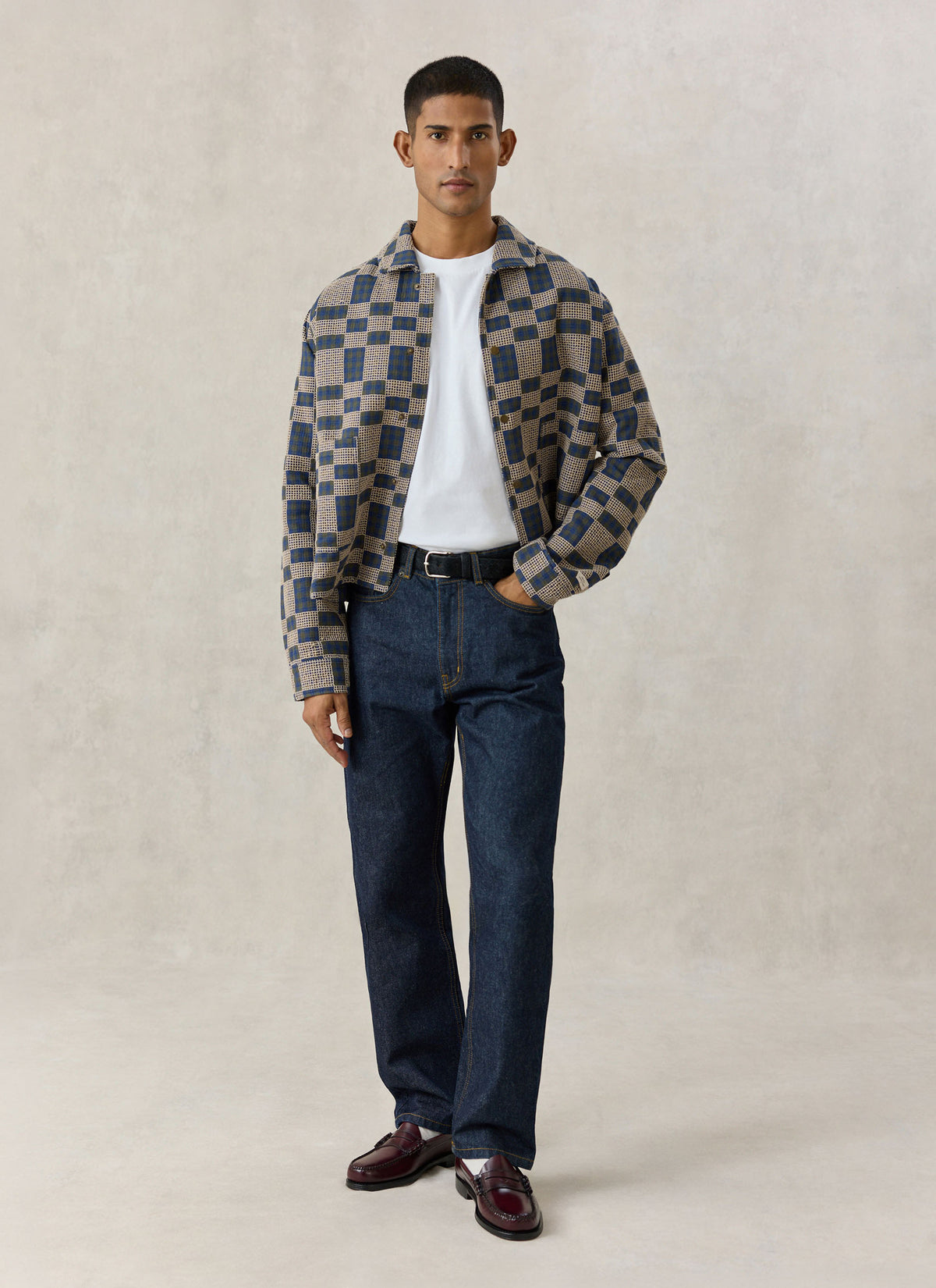 A model wearing the navy Percival grid check overshirt in cotton with dark jeans against a neutral studio backdrop.
