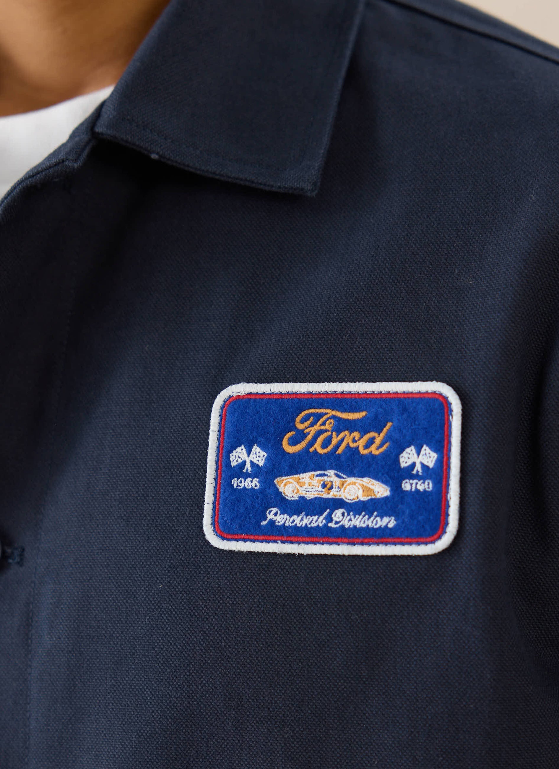 Navy Ford x Percival cotton canvas jacket detail, showing the GT40 motorsport-inspired embroidered chest patch.
