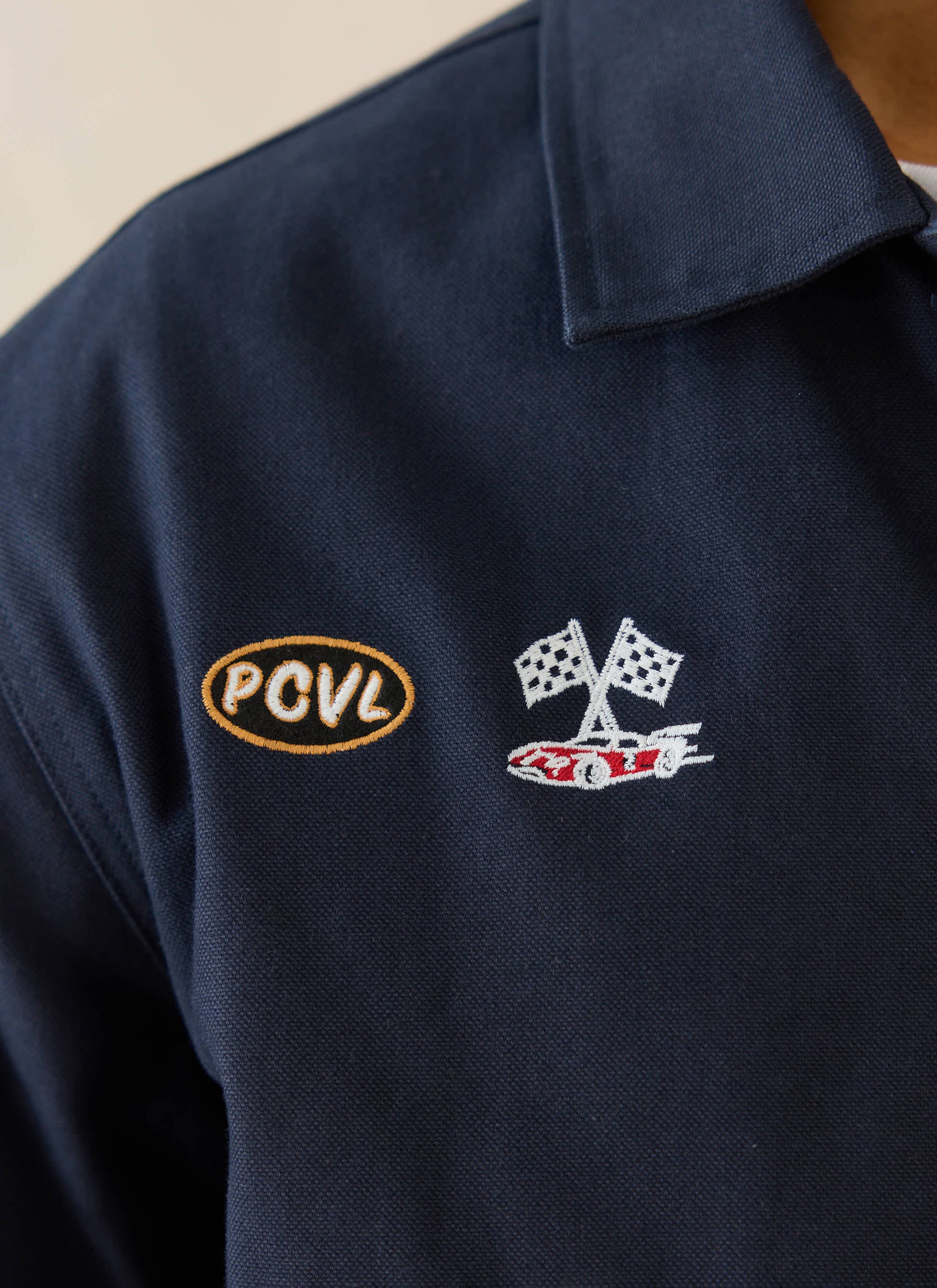 Close-up of the navy cotton canvas Ford x Percival jacket featuring PCVL and motorsport embroidery.