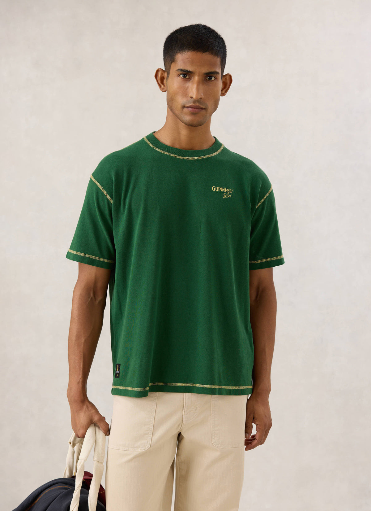 Model wearing the forest green Guinness x Percival oversized T-shirt, showing chest embroidery and contrast stitching.