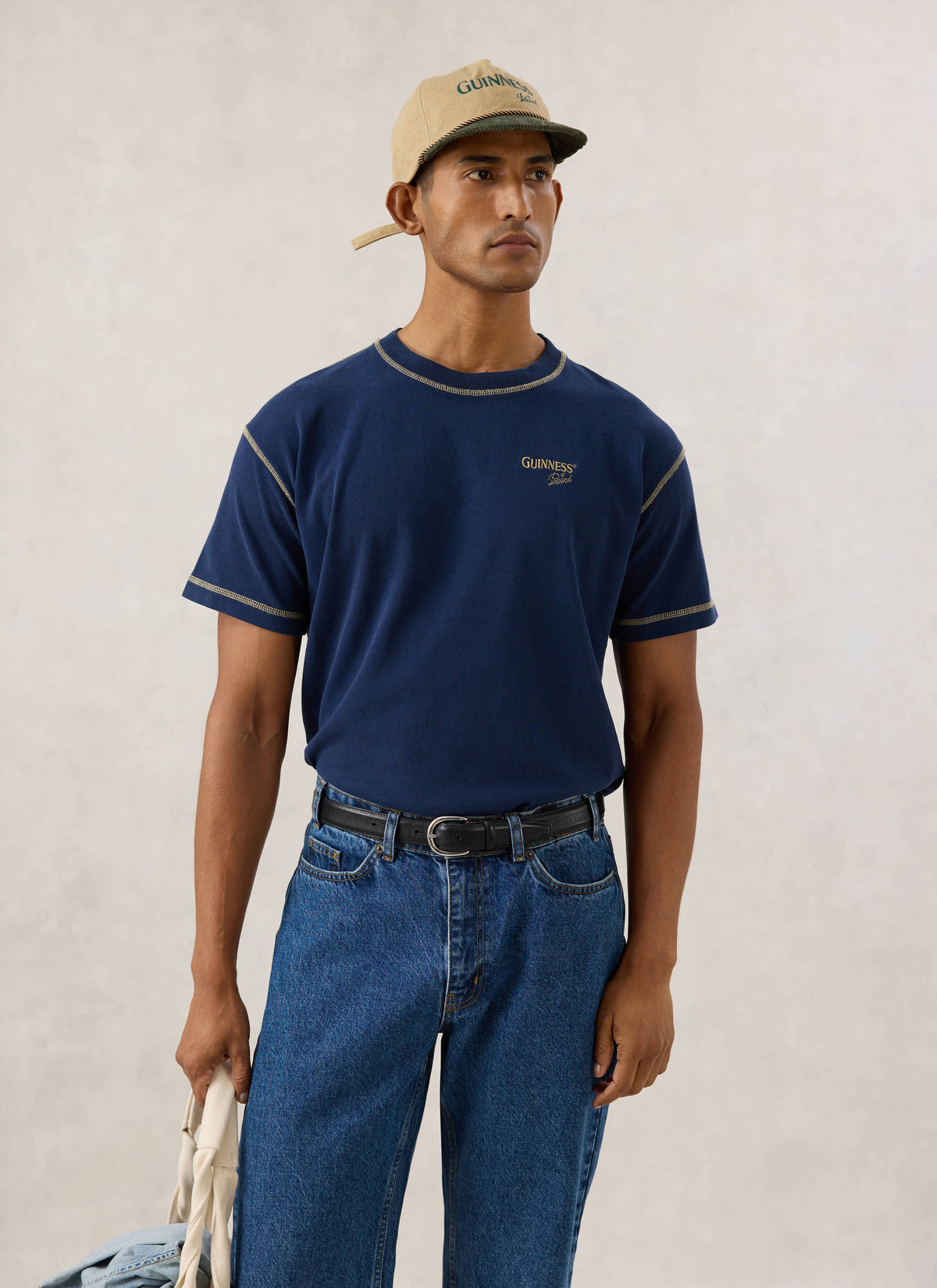 Model wearing the navy vintage wash T-shirt from Guinness x Percival, featuring contrast stitching and chest embroidery.