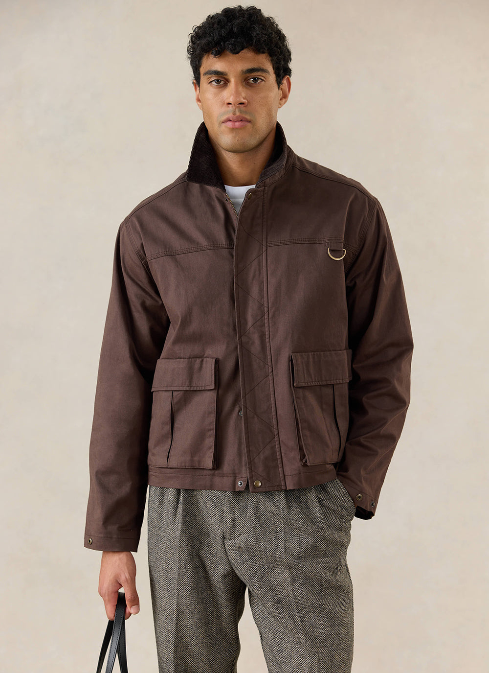 A model wears the Percival wax zip jacket in espresso brown featuring large patch pockets and a stand collar.