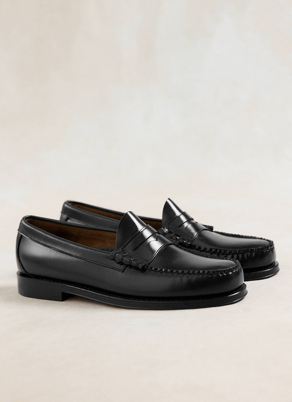 G.H. Bass black polished leather Weejun Larson penny loafers showcasing hand-stitched details and a classic slip-on design.