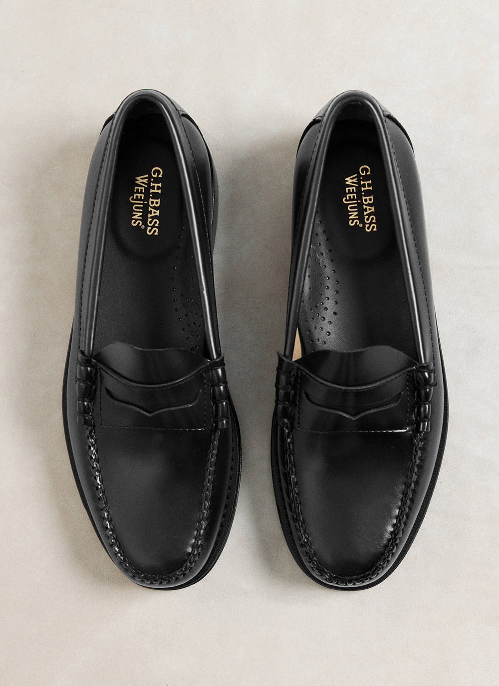 G.H. Bass black polished leather Weejun Larson penny loafers viewed from above, showing gold foil branding inside.