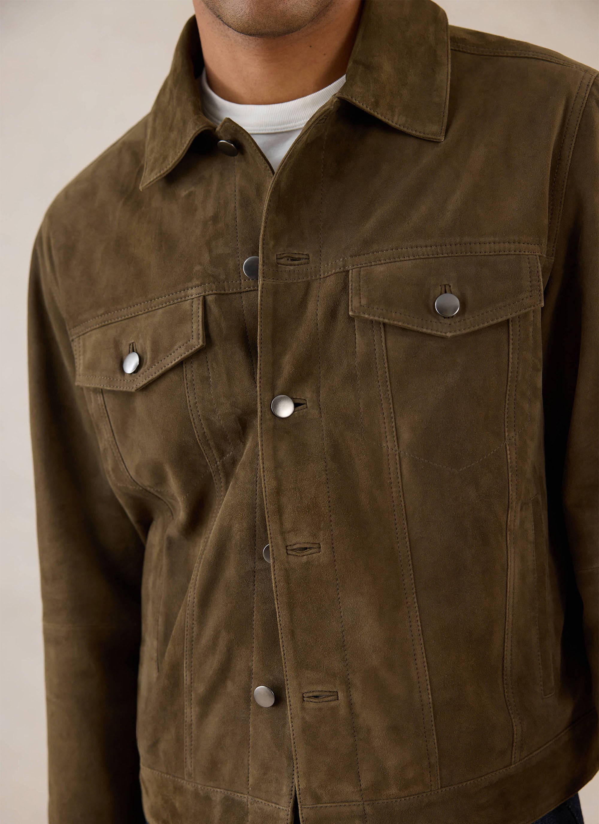 A close-up shot of the olive suede Western Jacket from Percival, highlighting the chest pockets and button details.