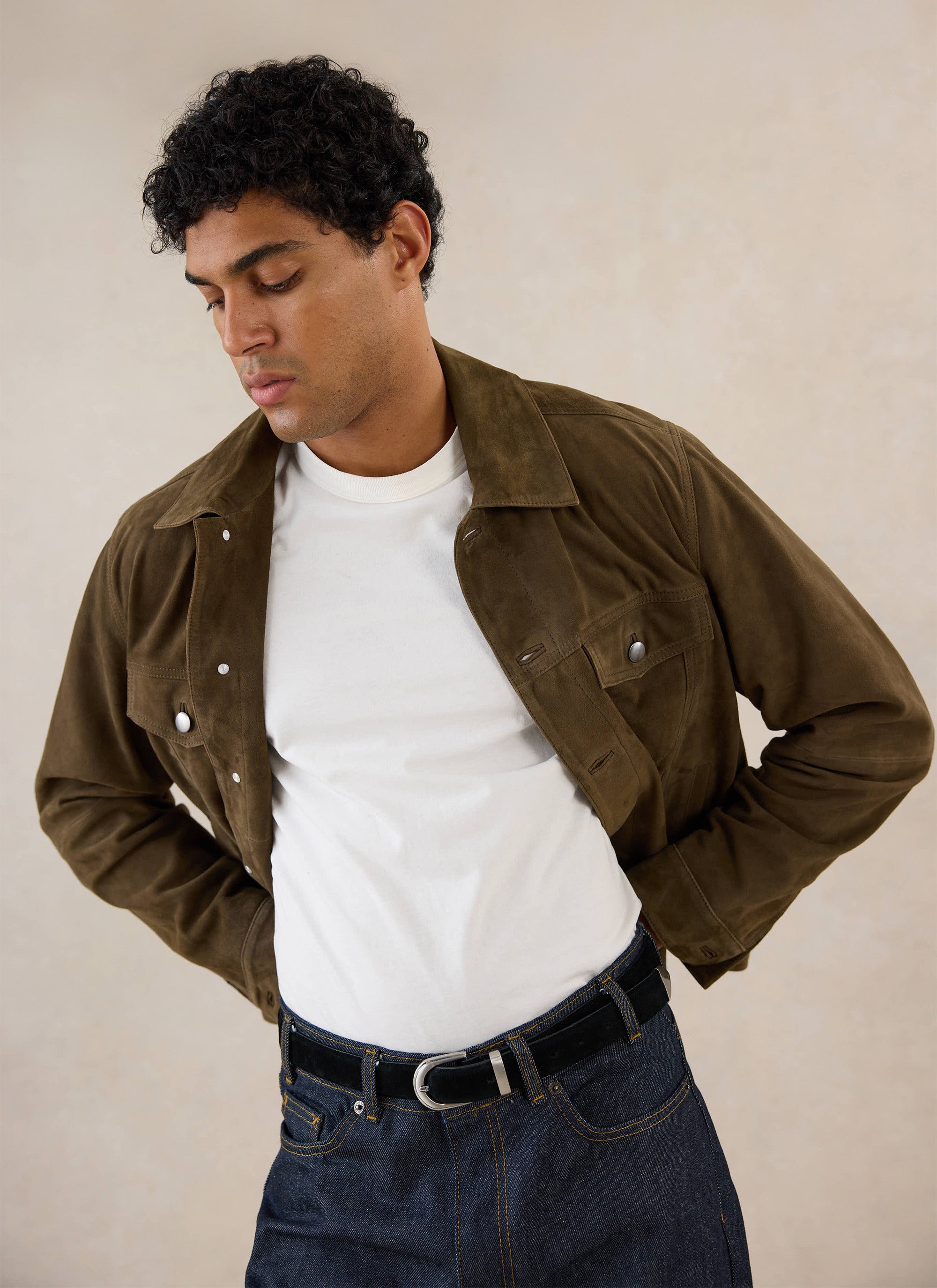 A model wears the olive Percival suede Western jacket over a white t-shirt and jeans in a studio shot.