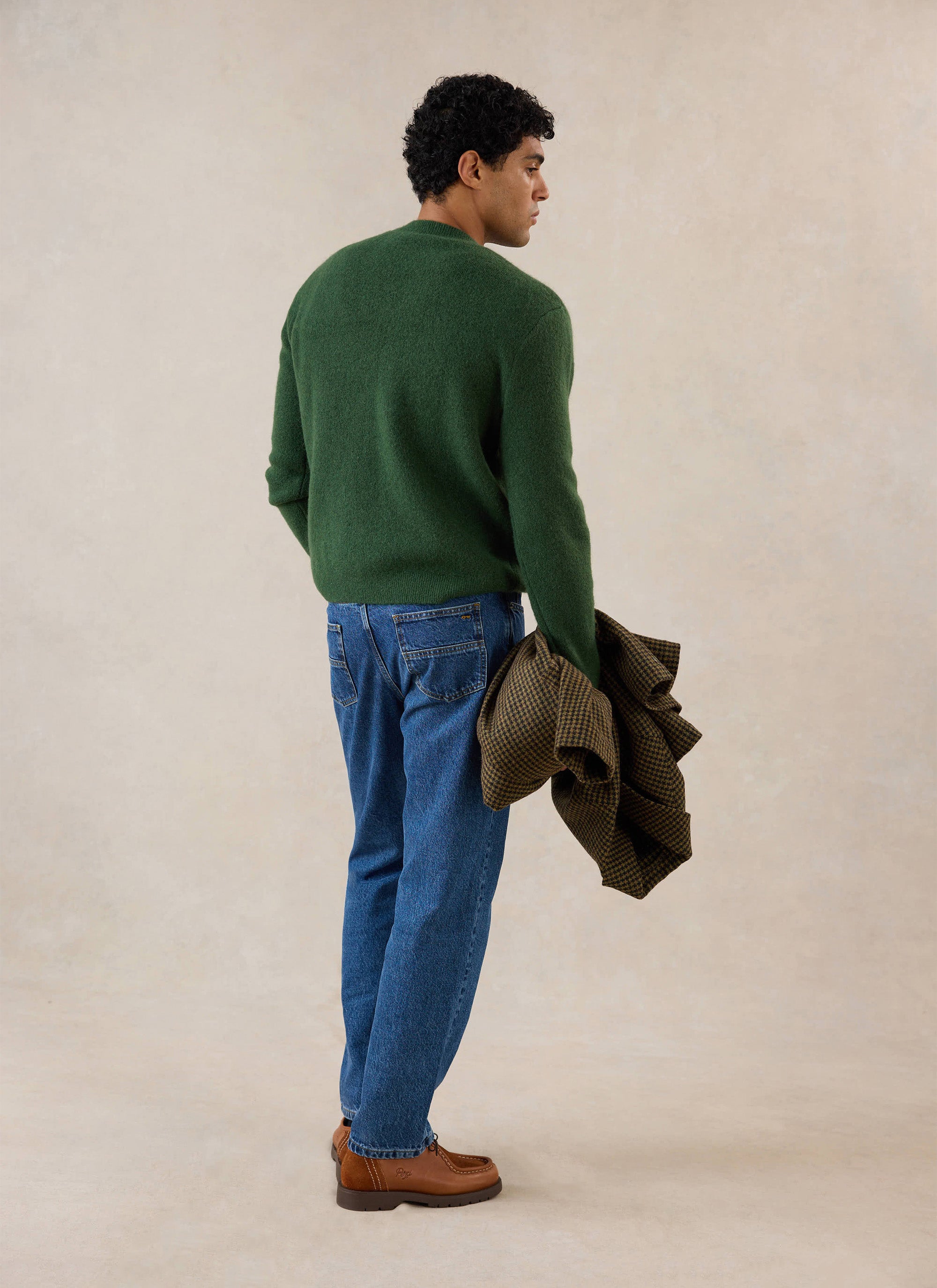 A model from behind wearing the forest green mohair Percival White Glove boxy crew neck jumper with blue jeans.