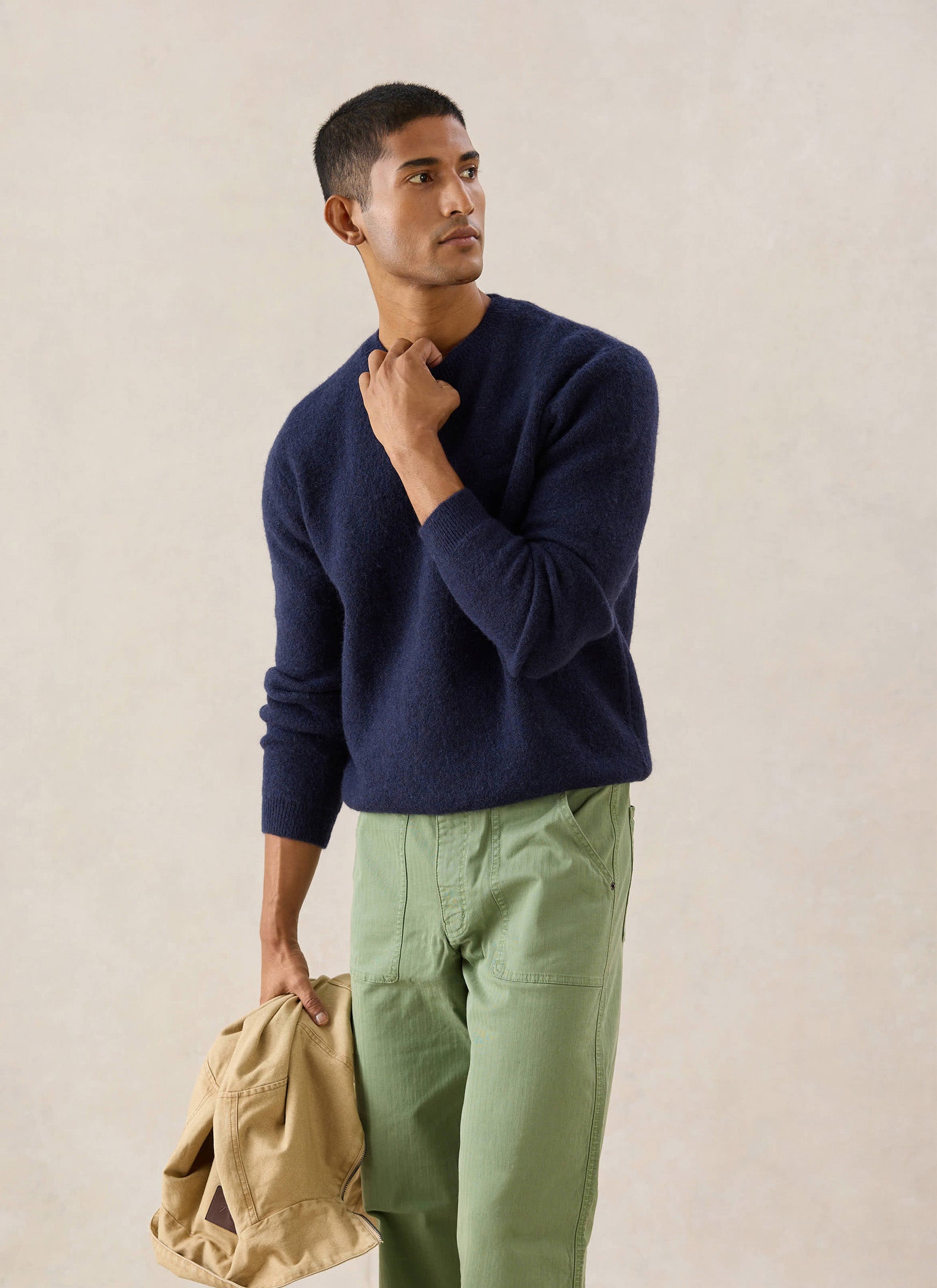 A model wears the navy mohair Percival White Glove boxy crew neck jumper with green trousers in a studio setting.
