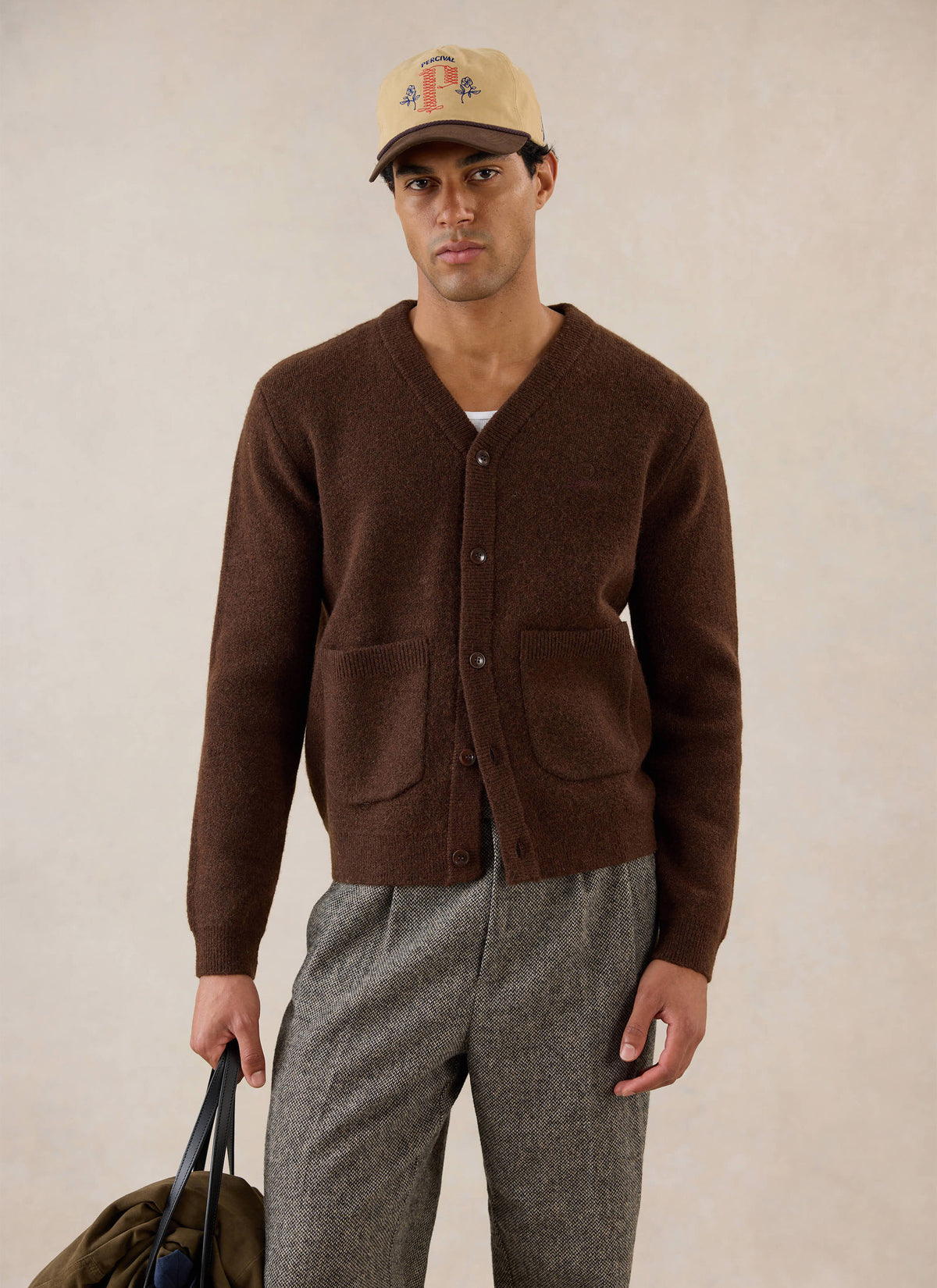 A model wears the Percival espresso brown mohair boxy cardigan with patch pockets and a matching cap in a studio setting.