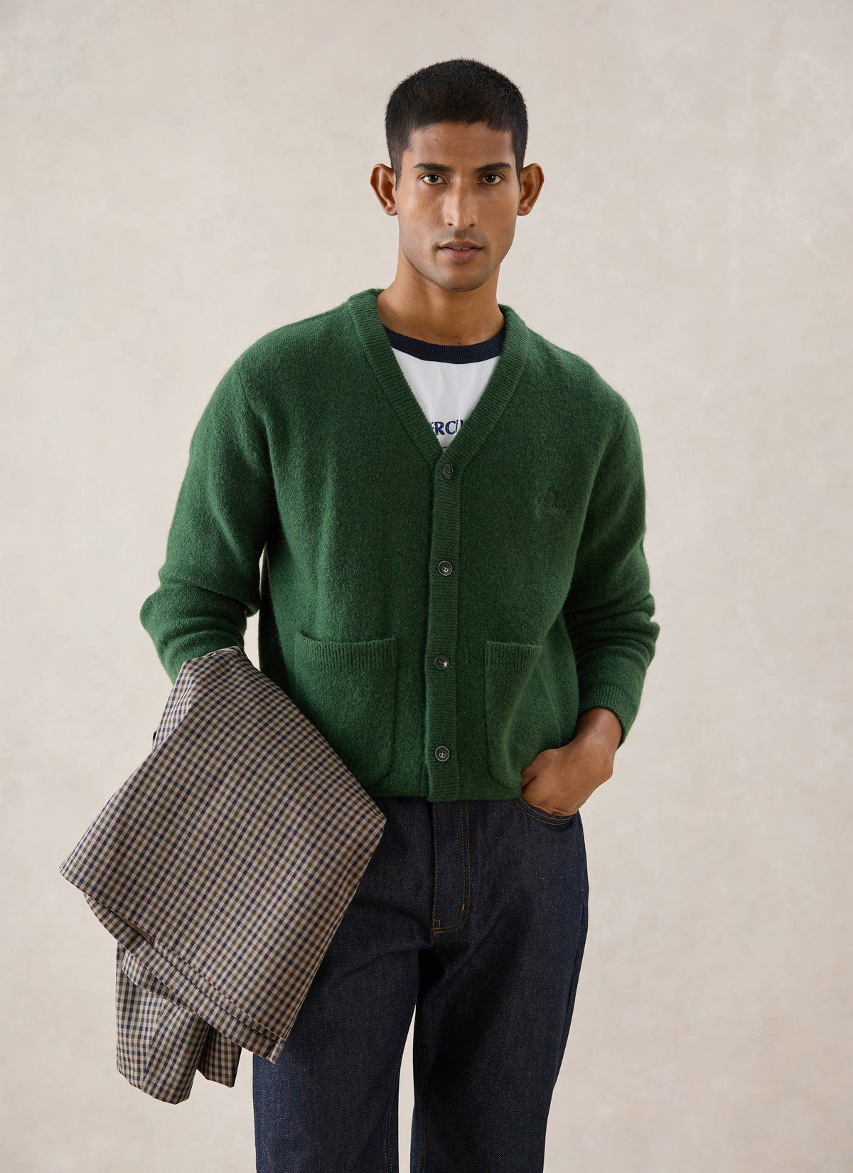A model wearing the Percival forest green mohair wool blend White Glove cardigan, holding a patterned jacket.