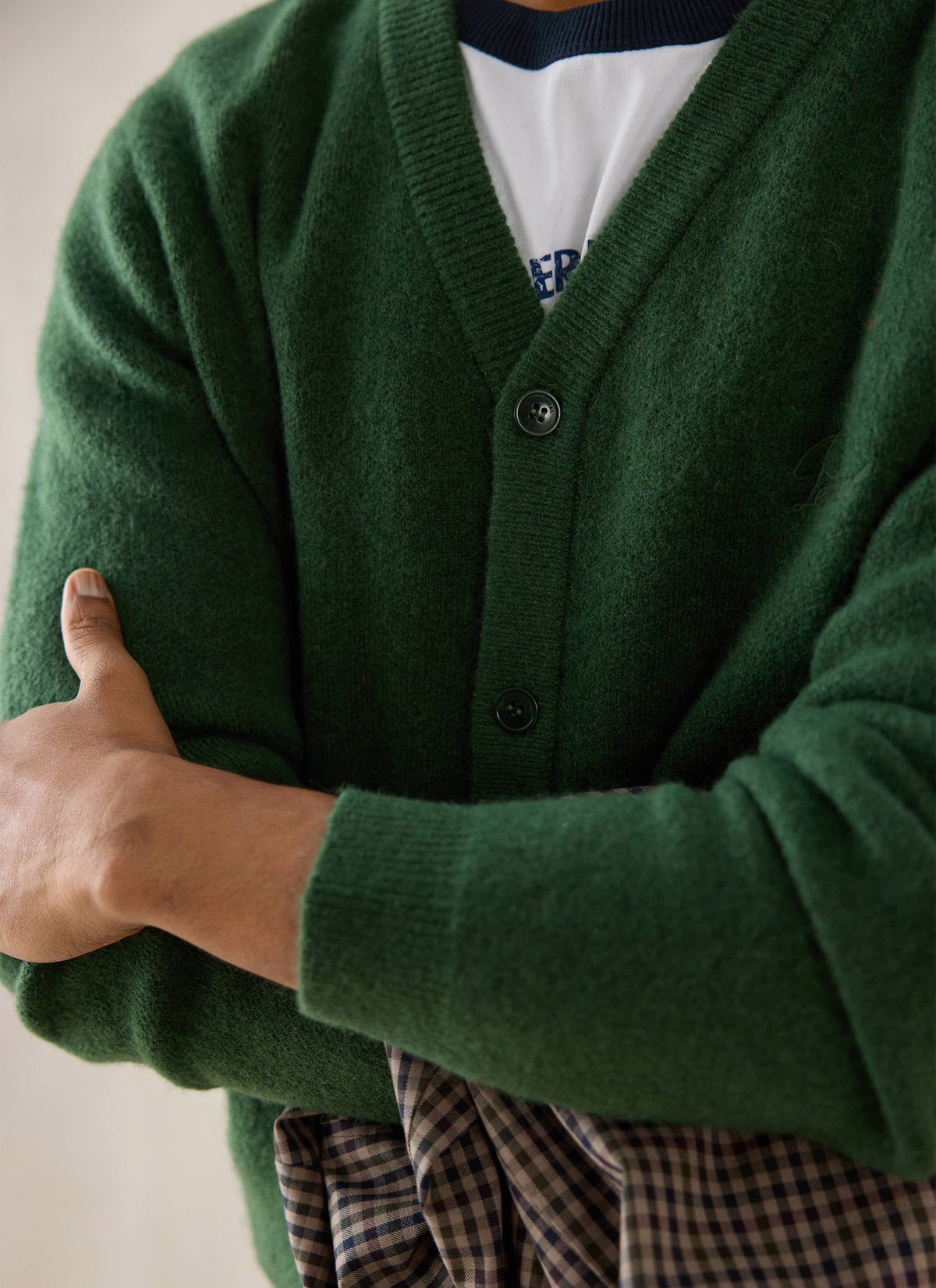 Close-up of a forest green Percival mohair wool blend cardigan on a model with arms crossed.