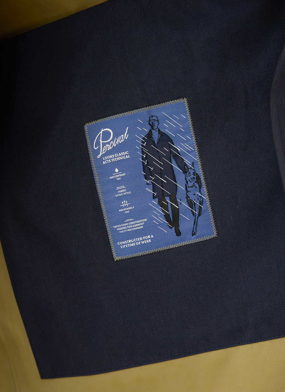 Interior label detailing waterproof features inside the Percival Wilson Long Trench Coat in midnight and olive.