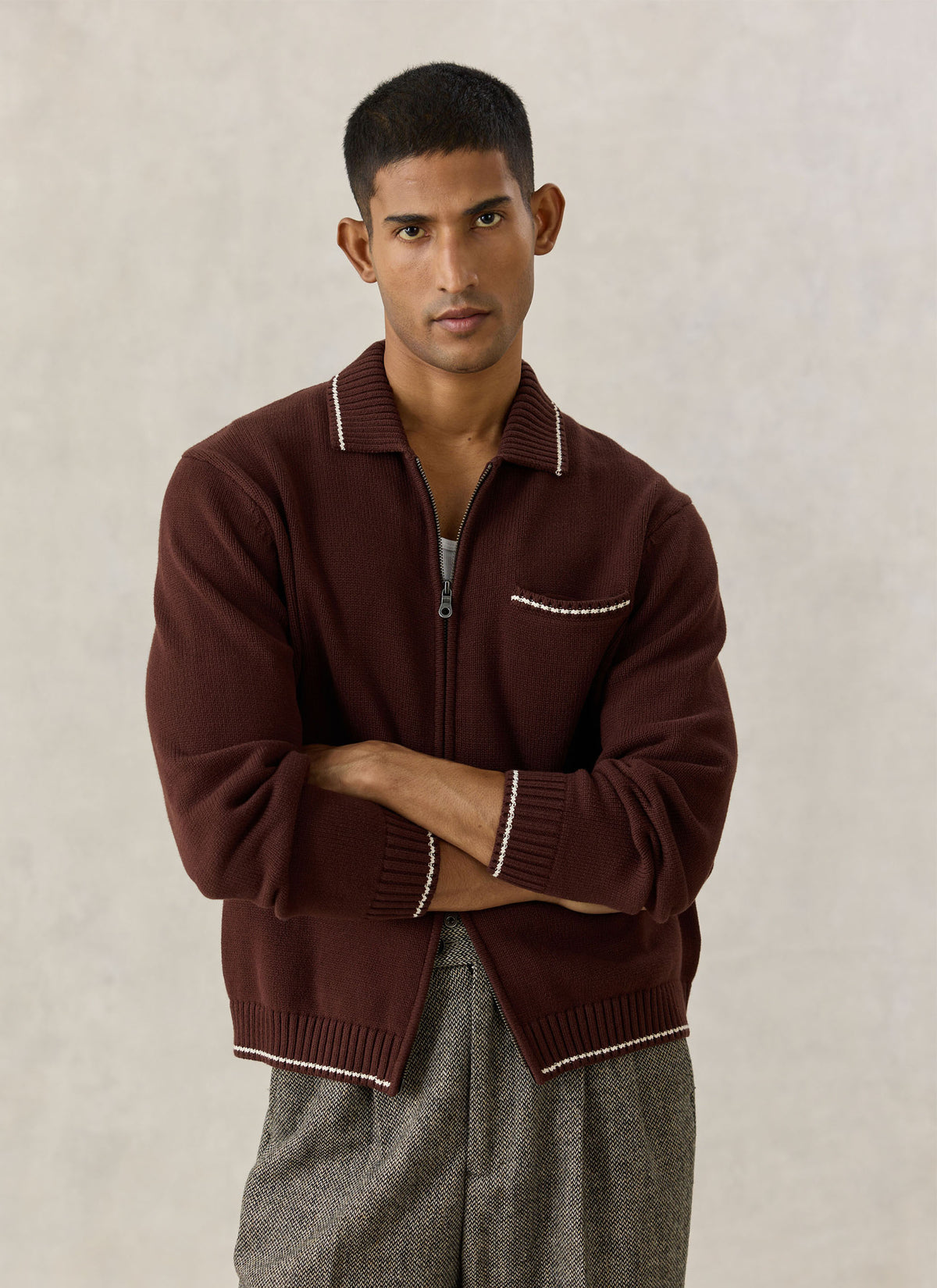 A model wearing the Percival Gardner dense knitted zip cardigan in espresso brown with contrast tipping.