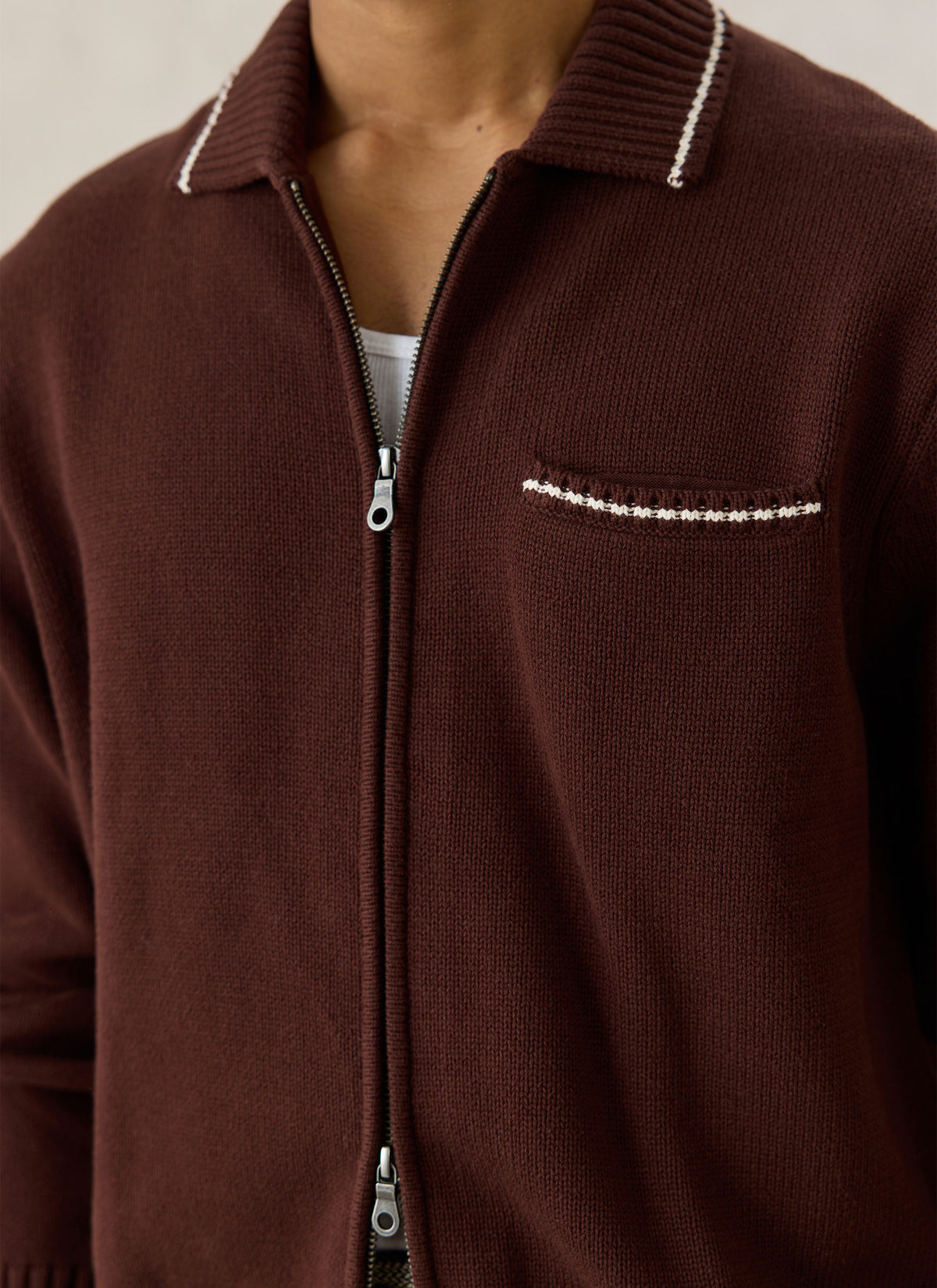 A close-up of the Percival Gardner zip cardigan in espresso, showing the chest pocket and contrast tipping.