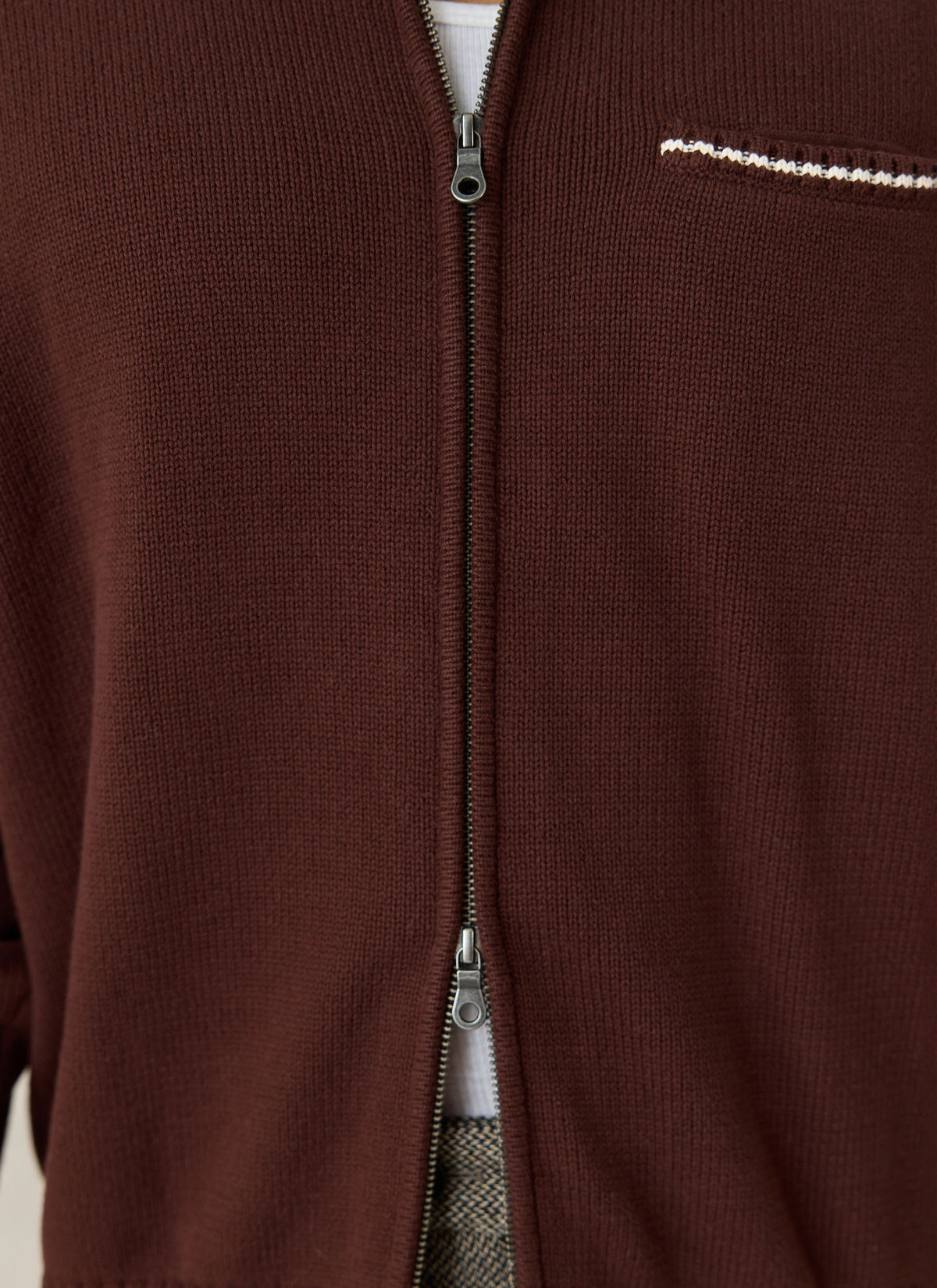 A close-up of the Gardner espresso brown cotton zip cardigan by Percival showing the two-way zip and chest pocket.