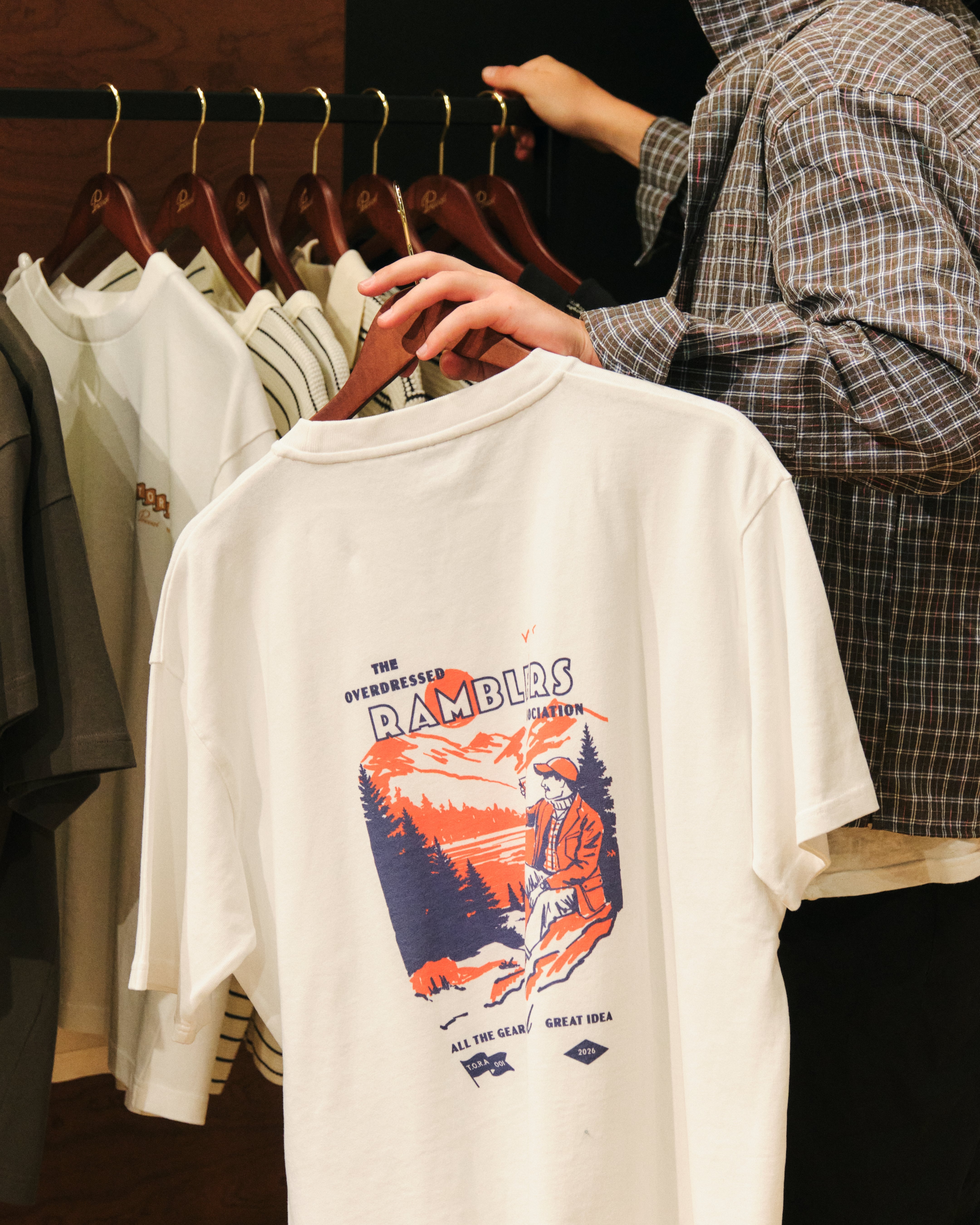 Customer holding a limited edition graphic t-shirt exclusive to the Percival menswear pop-up shop inside Selfridges Birmingham Bullring.